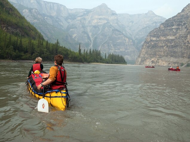 <p class="p1"><strong>Quintessential Canoe Country</strong></p><p class="p1">No one returns from the Nahanni unchanged. It’s too big, too old, too wild.</p><p class="p2">The morphing begins as visitors soar west in a Twin Otter plane from Fort Simpson, in the Northwest Territories. Below, vast boreal plains reach toward cave-riddled karstlands of the Ram Plateau. Soon descent begins into <a href="http://travel.nationalgeographic.com/travel/countries/canada-guide/">Canada’s</a> deepest river canyons—a 200-mile ancient waterway, home to the Dene people for thousands of years. “Many say if the trip ended here, they’d have gotten their money’s worth,” says veteran Nahanni guide Neil Hartling with a chuckle.</p><p class="p2">But go farther along the Nahanni River, and Virginia Falls—or what in the Dene tongue translates to “big water falling”—thunders as it drops 302 feet, nearly twice the height of Niagara. Rare orchids thrive in its billowing mist.</p><p class="p2">Canada’s most revered river expedition brims with lore of Klondike gold prospectors, trappers, adventurers, and their gory misfortunes in places named Headless Creek and Deadmen Valley. Ahead: the Gate’s plunging sandstone chasm, neck-high mud baths at Kraus Hotsprings, maybe a tin plate of arctic char riverside.</p><p class="p2">In a nation built on legends of daring voyageurs paddling its myriad waterways, the Nahanni is deep Canada—<em>le Canada profond.</em> It beguiled late Canadian Prime Minister Pierre Elliott Trudeau. A master canoeist, he paddled here in 1970 and was instrumental in having it made a national park reserve. With the help of his eldest son, Justin (now vying for his father’s old job), the reserve has grown sixfold.</p><p class="p2">So yes, the Nahanni leaves a mark. Once asked by a journalist what job he’d want if he weren’t prime minister, Trudeau smiled and replied, no hesitation, “I’d be a guide on the Nahanni.” <em>—Liz Beatty</em></p><p><strong> Travel Tips </strong></p><p><strong>When to Go:</strong> Paddling season runs from mid-June to September. Early season brings nearly 24 hours of daylight (and more insects), while the late season offers the possibility of seeing the northern lights.</p><p><strong>How to Get Around:</strong> The safest and most convenient way to explore Nahanni is via a paddle trip led by a registered, licensed outfitter such as <a href="http://www.nahanni.com" target="_blank">Nahanni River Adventures</a> or Black Feather. Trips vary in length and skill level and can include hiking and rafting. Floatplane daytrips to <a href="http://www.simpsonair.ca" target="_blank">Nahanni via Simpson Air</a> are a less taxing yet more expensive way to see Virginia Falls and surrounding areas.</p><p><strong>Where to Stay:</strong> Reserve two nights (the maximum allowed) at the <a href="http://www.pc.gc.ca/pn-np/nt/nahanni/visit/visit5.aspx" target="_blank">Virginia Falls Campground</a>, accessible by two- to three-day paddling trip from Rabbitkettle Lake. Or travel by floatplane to remote Nahanni Mountain Lodge on the eastern shore of pristine Little Doctor Lake. Originally built by northern pioneers Gus and Mary Kraus of Kraus Hotsprings fame (Gus is fabled to have advised Pierre Trudeau on the original park boundaries), the fishing lodge has four basic log cabins, and a fire pit and grill on the beach to cook the perch or trout you catch for supper.</p><p><strong> Where to Eat or Drink:</strong> Food is not available in the park. Guided trips include meals, drinks, and snacks. Menus typically include some local delicacies like arctic char, Taku River salmon, and caribou.</p><p><strong> Cultural Tip:</strong> You have to <a href="http://www.pc.gc.ca/pn-np/nt/nahanni/activ/activ2.aspx" target="_blank">register</a> before embarking on a paddling trip in the park and de-register when you safely return. No reservations are required for day-use visitors, but a fee (about $24) must be deposited in a collection box at the Virginia Falls information kiosk.</p><p><strong> What to Read or Watch Before You Go:</strong> British-born adventurer Raymond Patterson’s <a href="http://www.amazon.com/Dangerous-River-The-R-M-Patterson/dp/1894898869" target="_blank"><em>The Dangerous River: Adventure on the Nahanni</em></a> (TouchWood Editions, 2009) chronicles his 1920s expeditions as one of the first outsiders to journey up the Nahanni River.</p><p><strong> Helpful Link:</strong> <a href="http://www.pc.gc.ca/pn-np/nt/nahanni/index.aspx" target="_blank"> Nahanni National Park</a></p><p><strong> Fun Fact:</strong> It’s been more than a century since the headless corpses of two gold prospectors were discovered in 1908 in what’s now Nahanni National Park Reserve. Yet their haunted legend lives on in park locations like Headless Creek and Headless Range.</p><p><strong> Insider Tip From Liz Beatty:</strong> I recommend Nahanni River Adventures (of the three licensed to guide here). Founder Neil Hartling has written two books about his three decades in this wilderness (he guided Justin Trudeau). Neil’s quiet, even-handed nature seems akin to what I imagine of Raymond M. Patterson.</p>