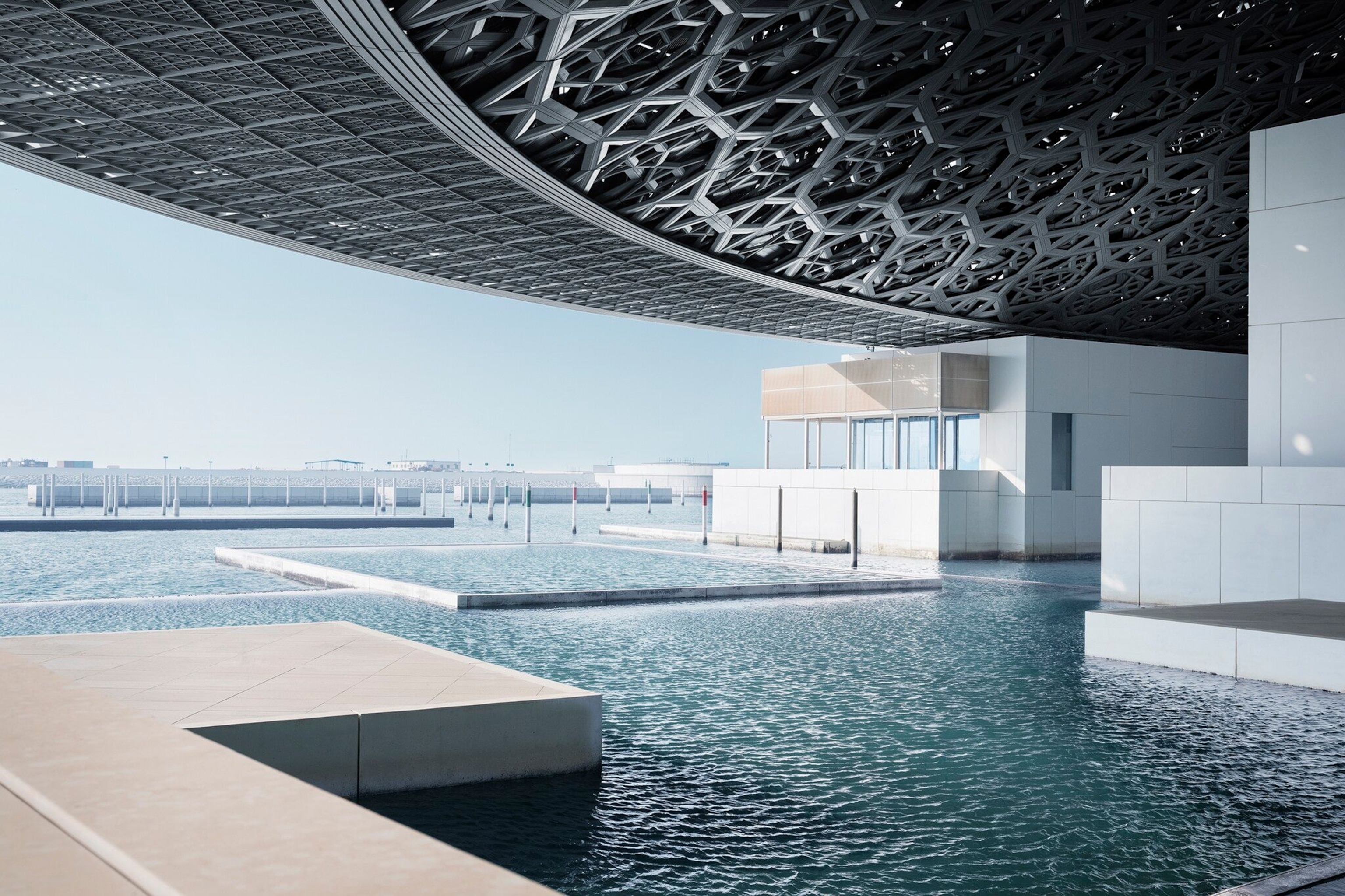 Expansive water features surrounded by metallic, chainmailesque patterns at the Louvre Abu Dhabi.
