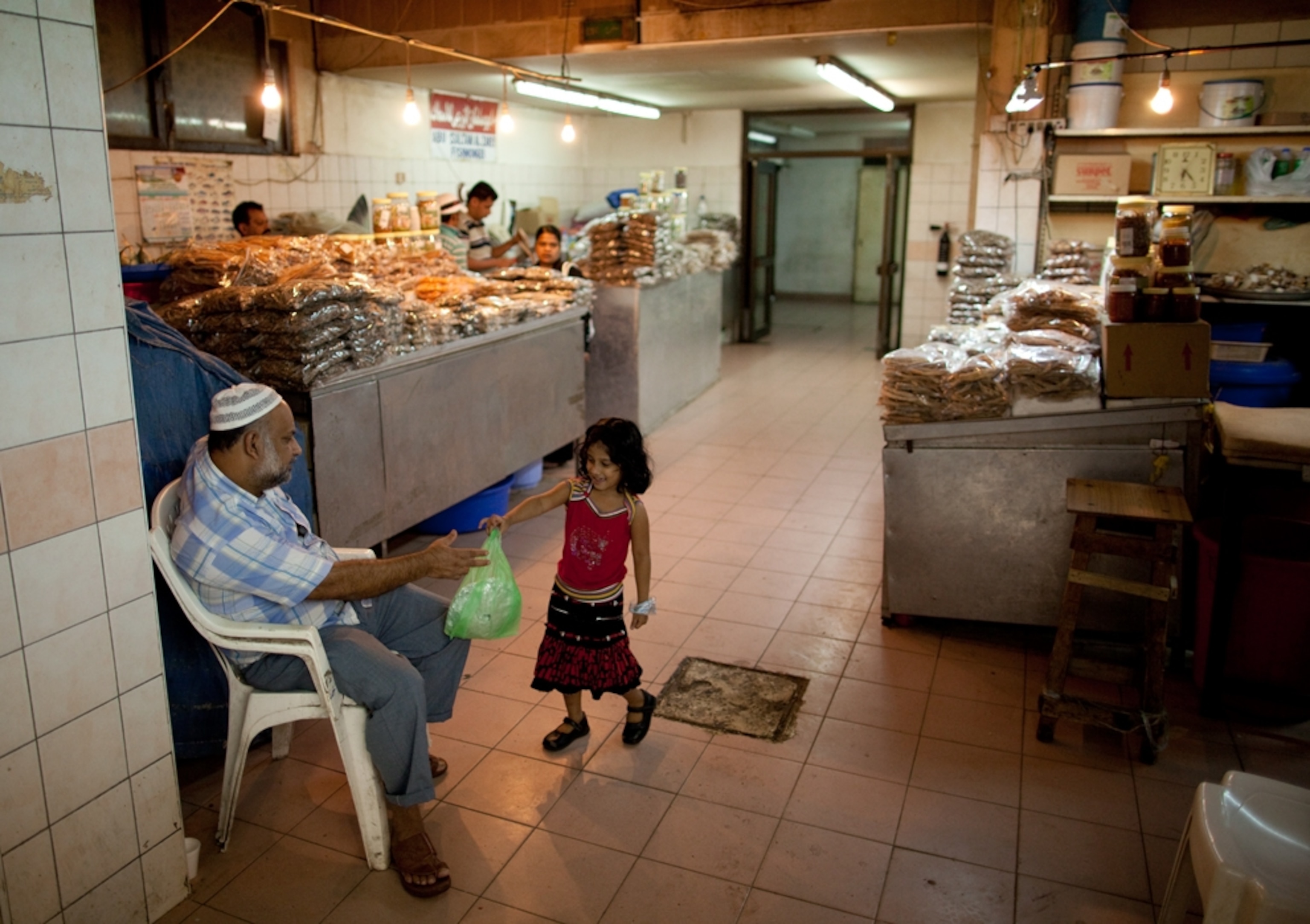 A young girl carries a bag of dried fish purchased from a food stall