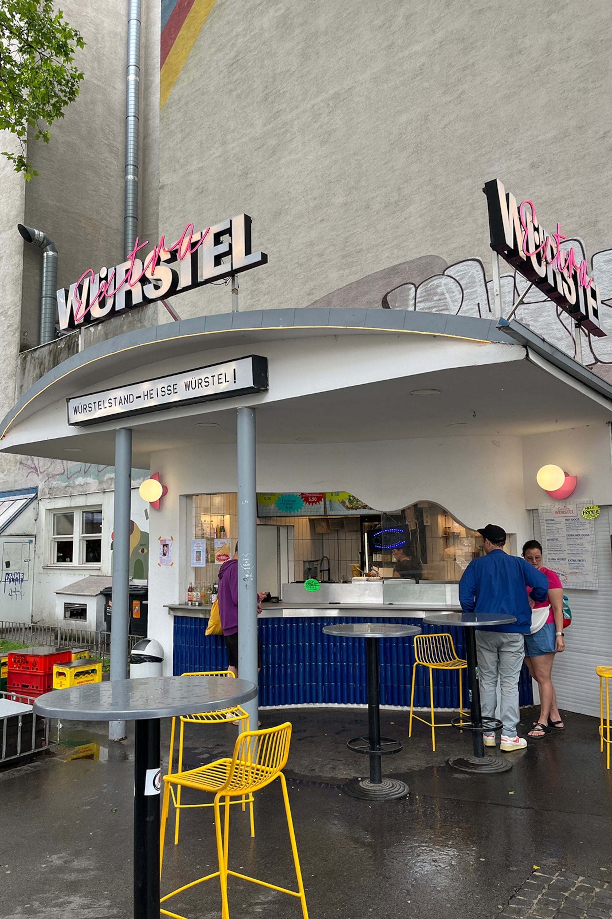 A simple, street-side kiosk with a metal frame and neon sign.