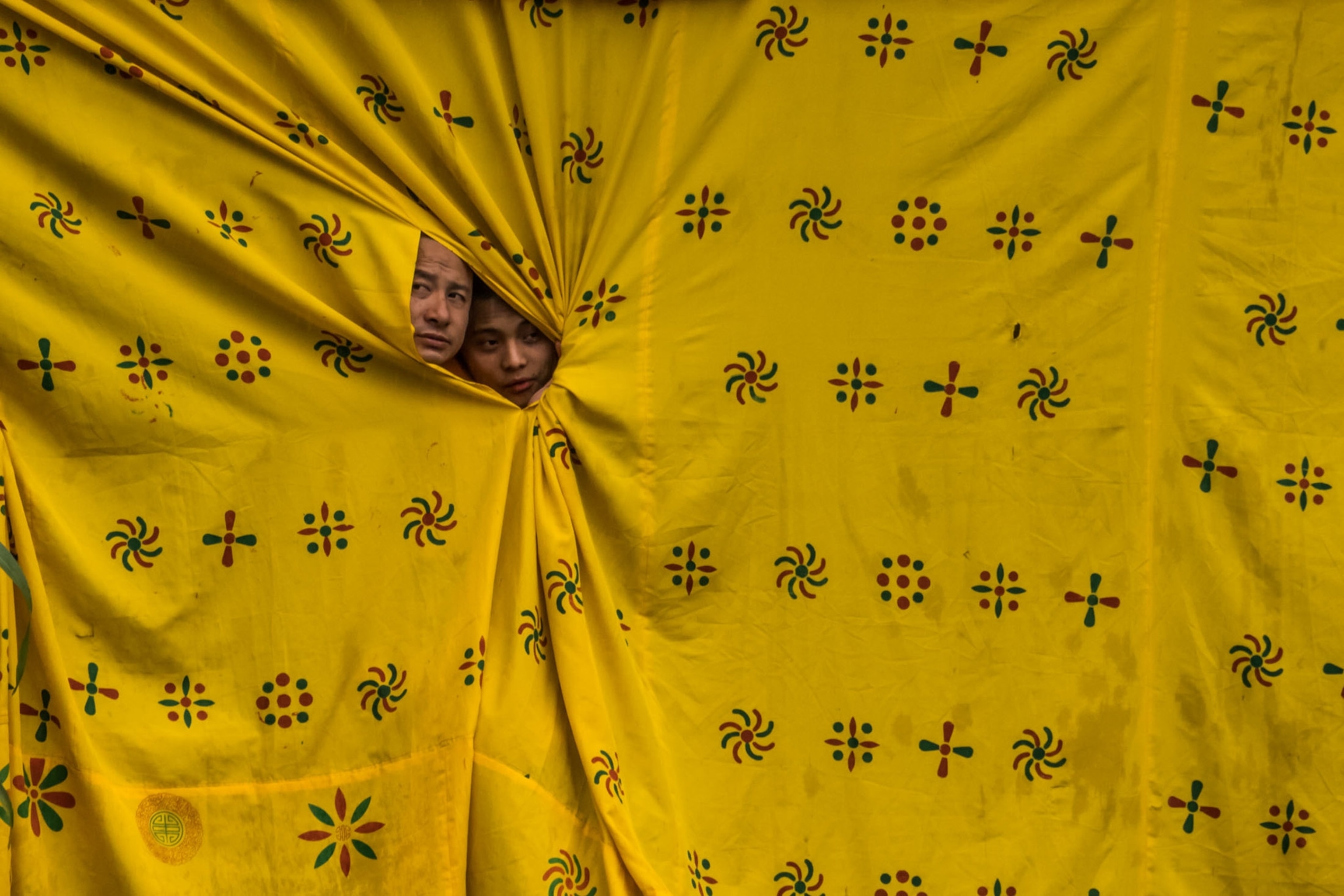 two monks peeking from a curtain at a festival at Bhutan