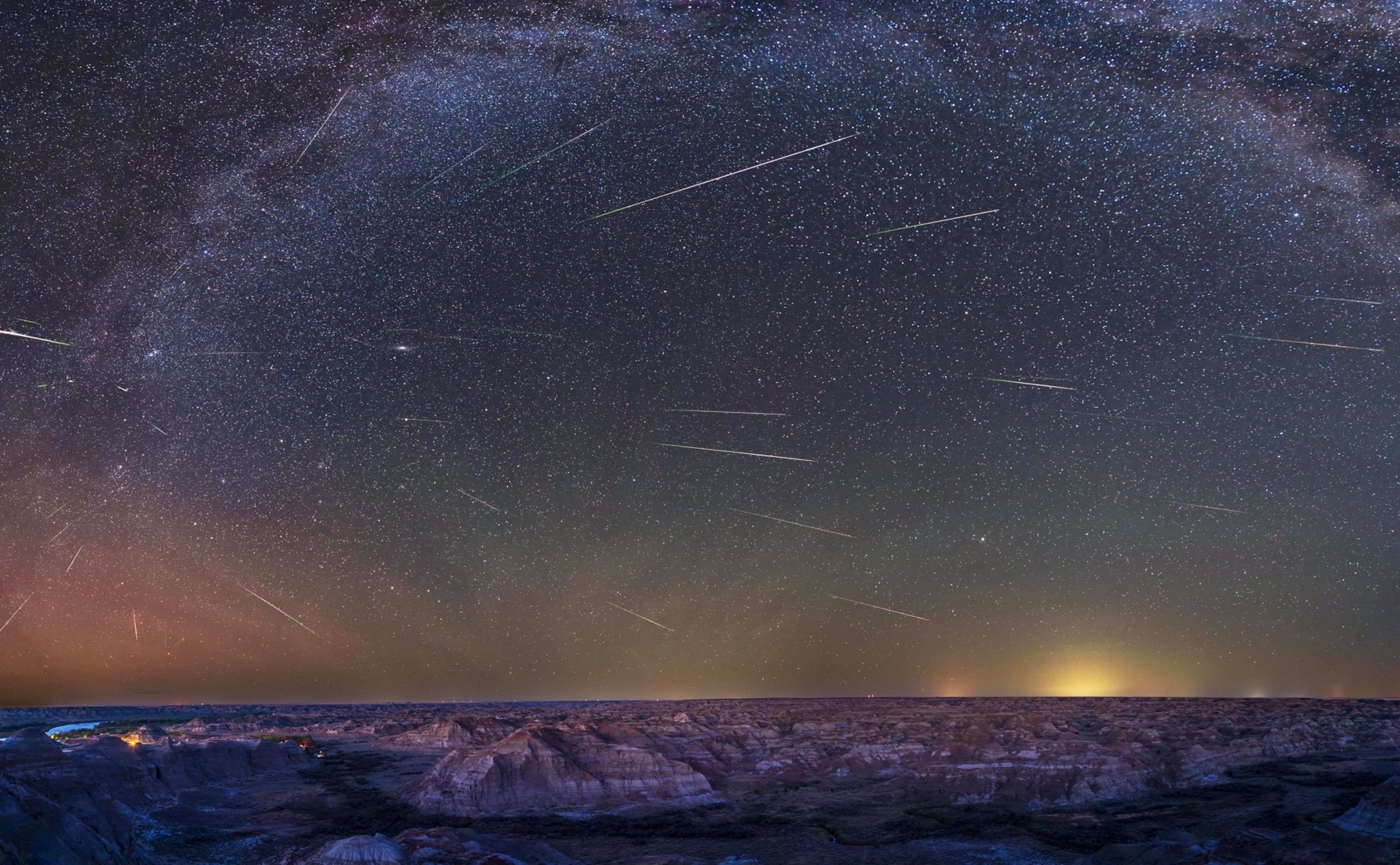 This is a panorama of the ground and sky framing the badlands of Dinosaur Provincial Park, in the Red Deer River valley in Alberta, with the summer sky above filled with three dozen meteors from the annual Perseid meteor shower