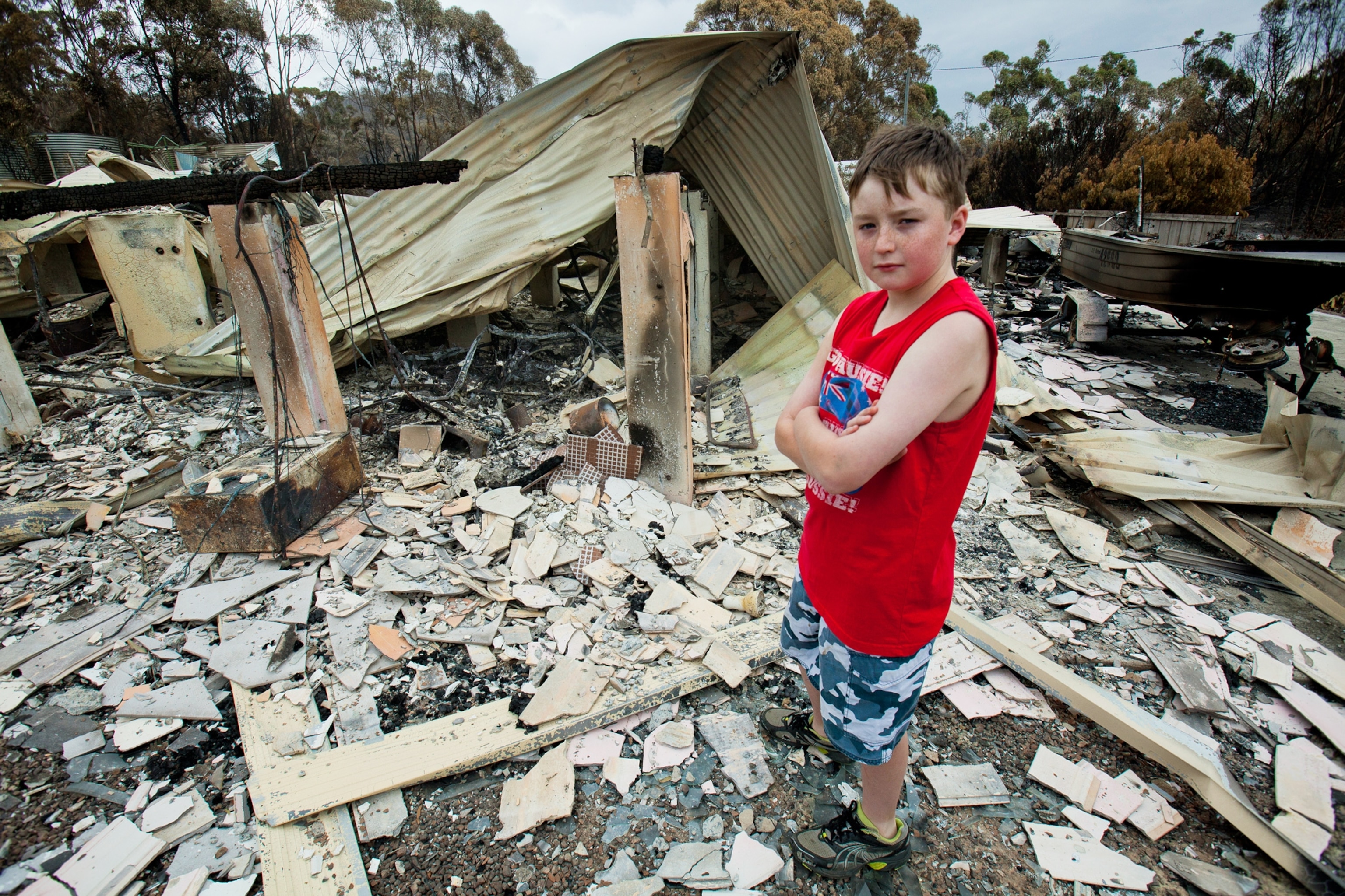 Australia wildfire picture - boy stands in ruins in Tasmania