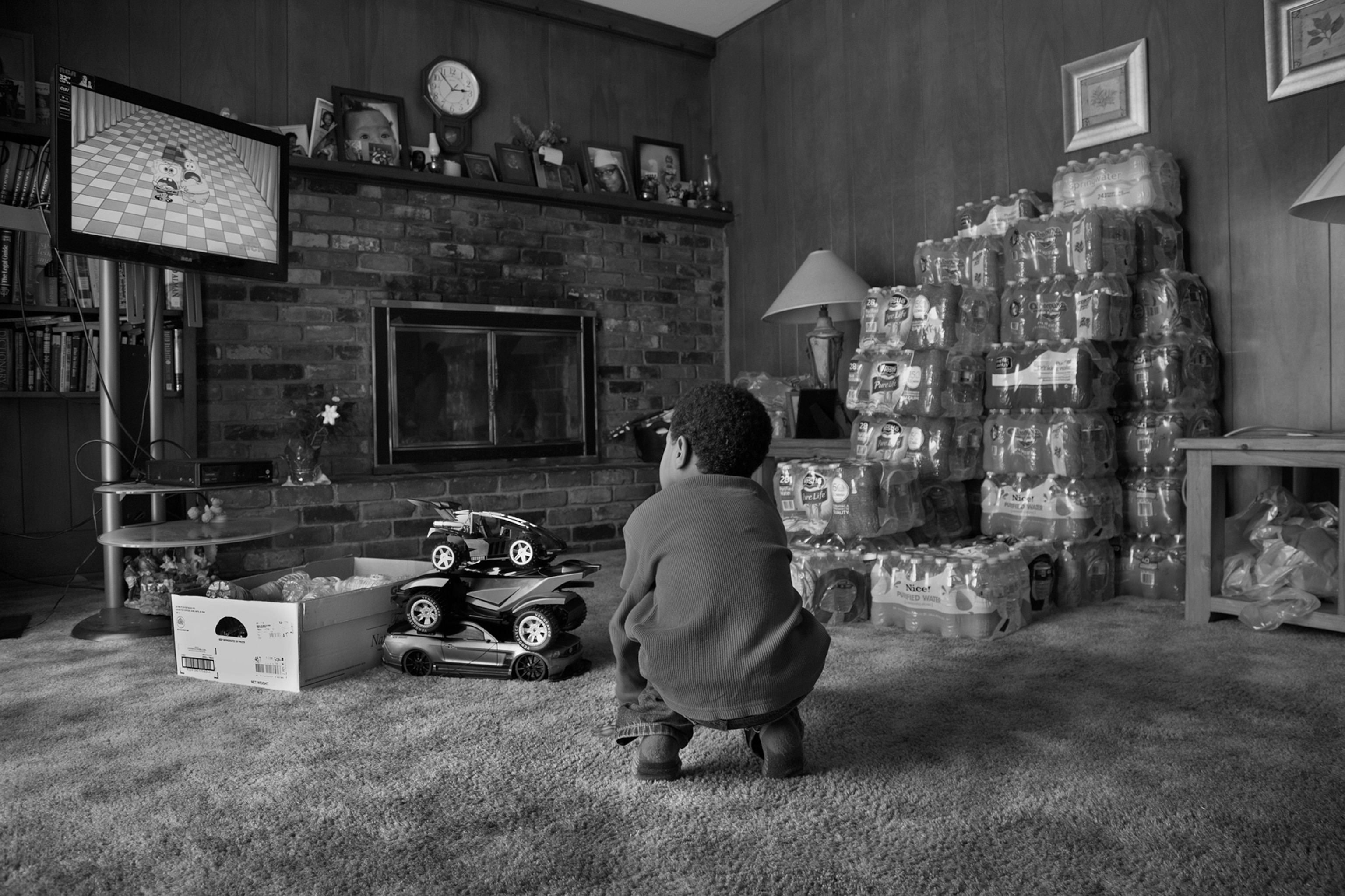 boy watching tv in room with water bottles