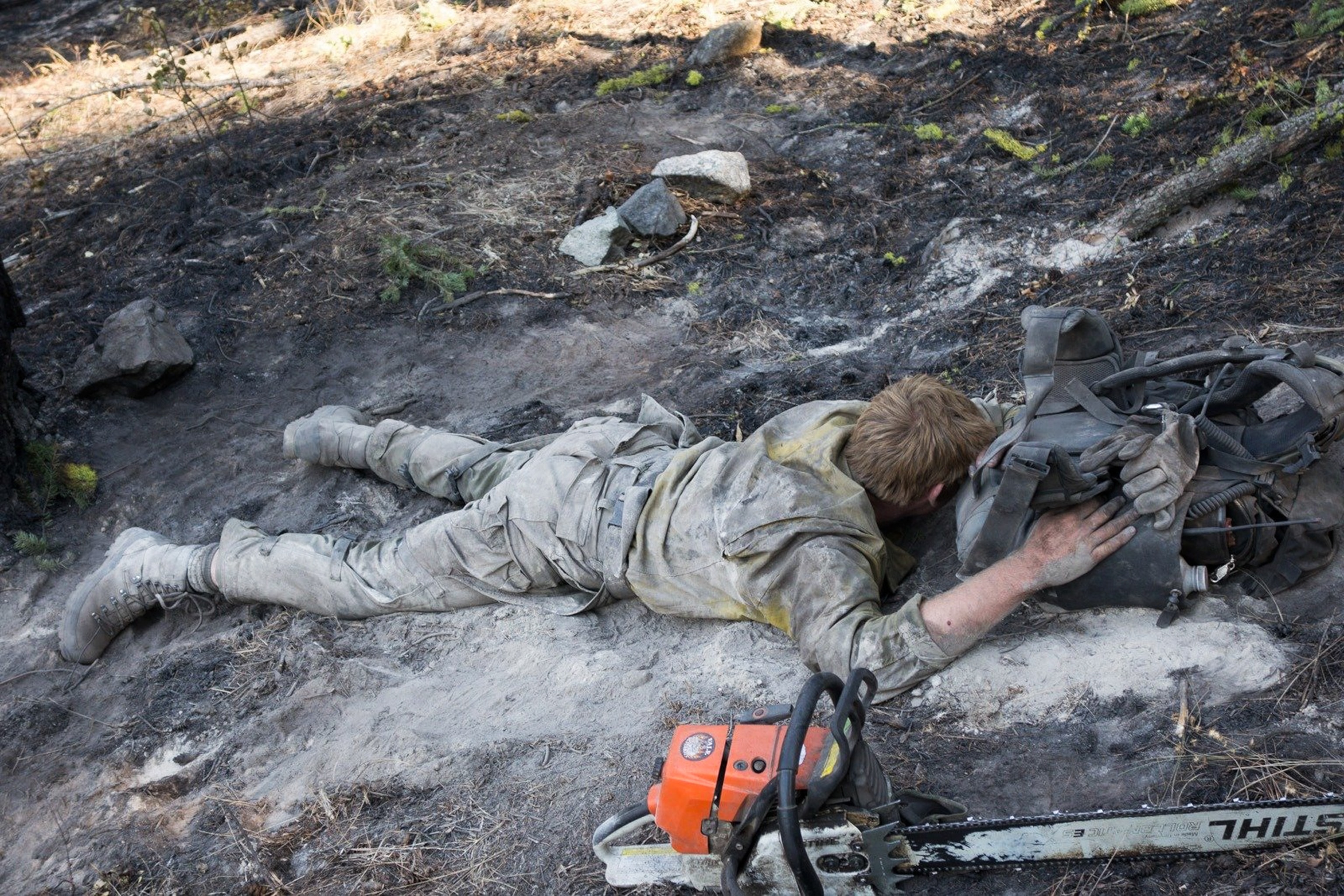 a firefighter covered in ash laying down for a rest at the Carlton Complex fire.