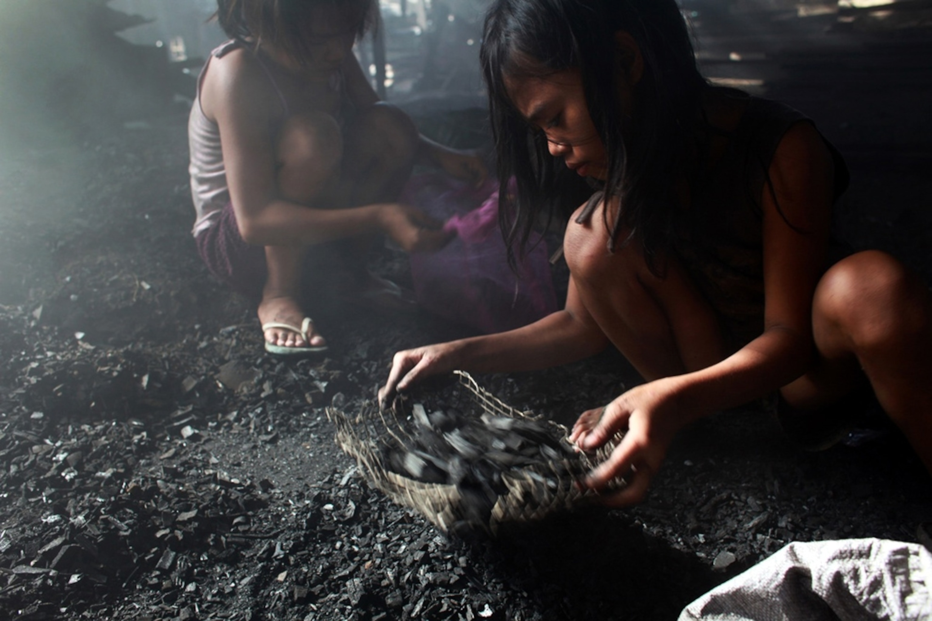 A girl sifts through charcoal in search of nails, Manila