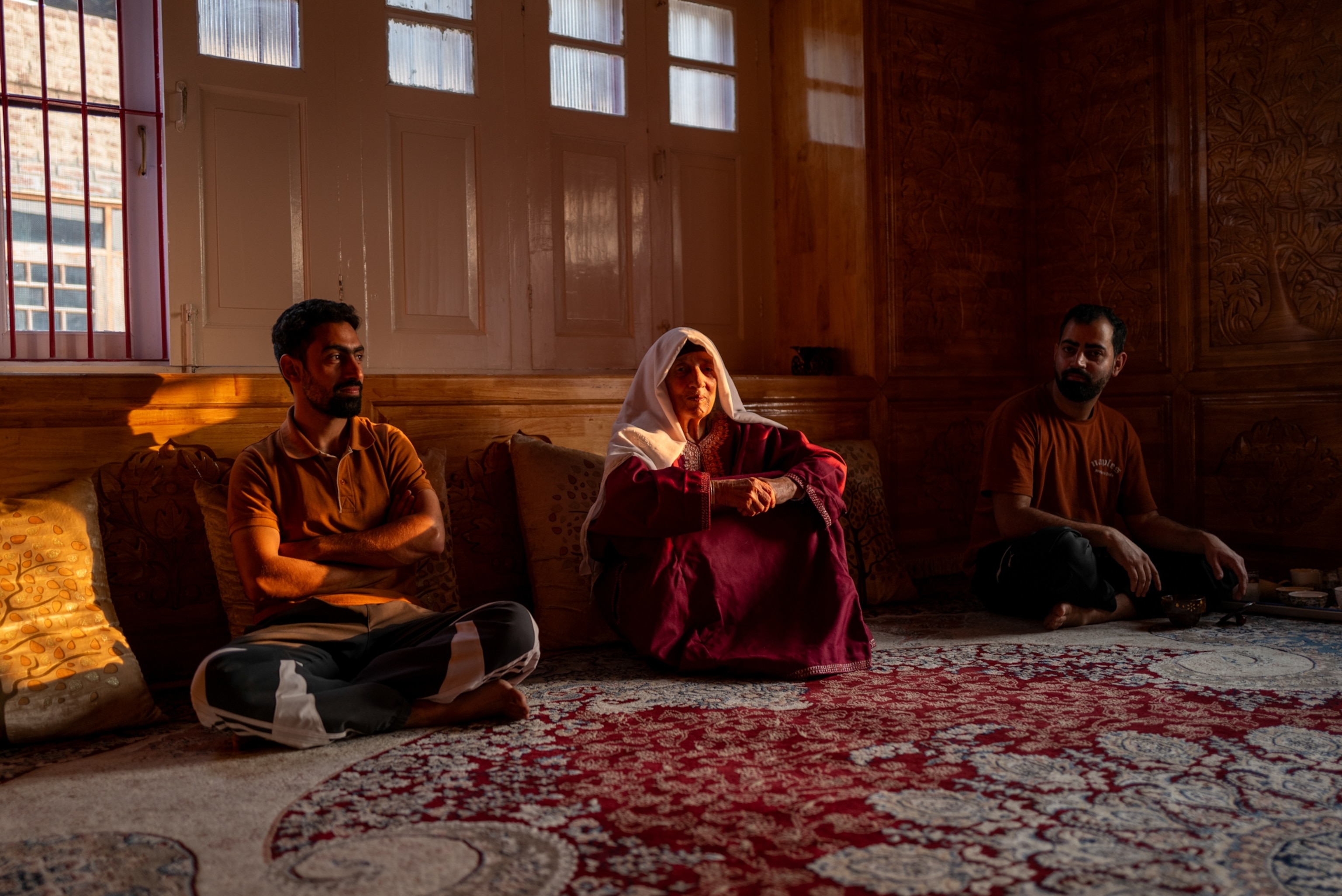 A family sit on a carpet together.