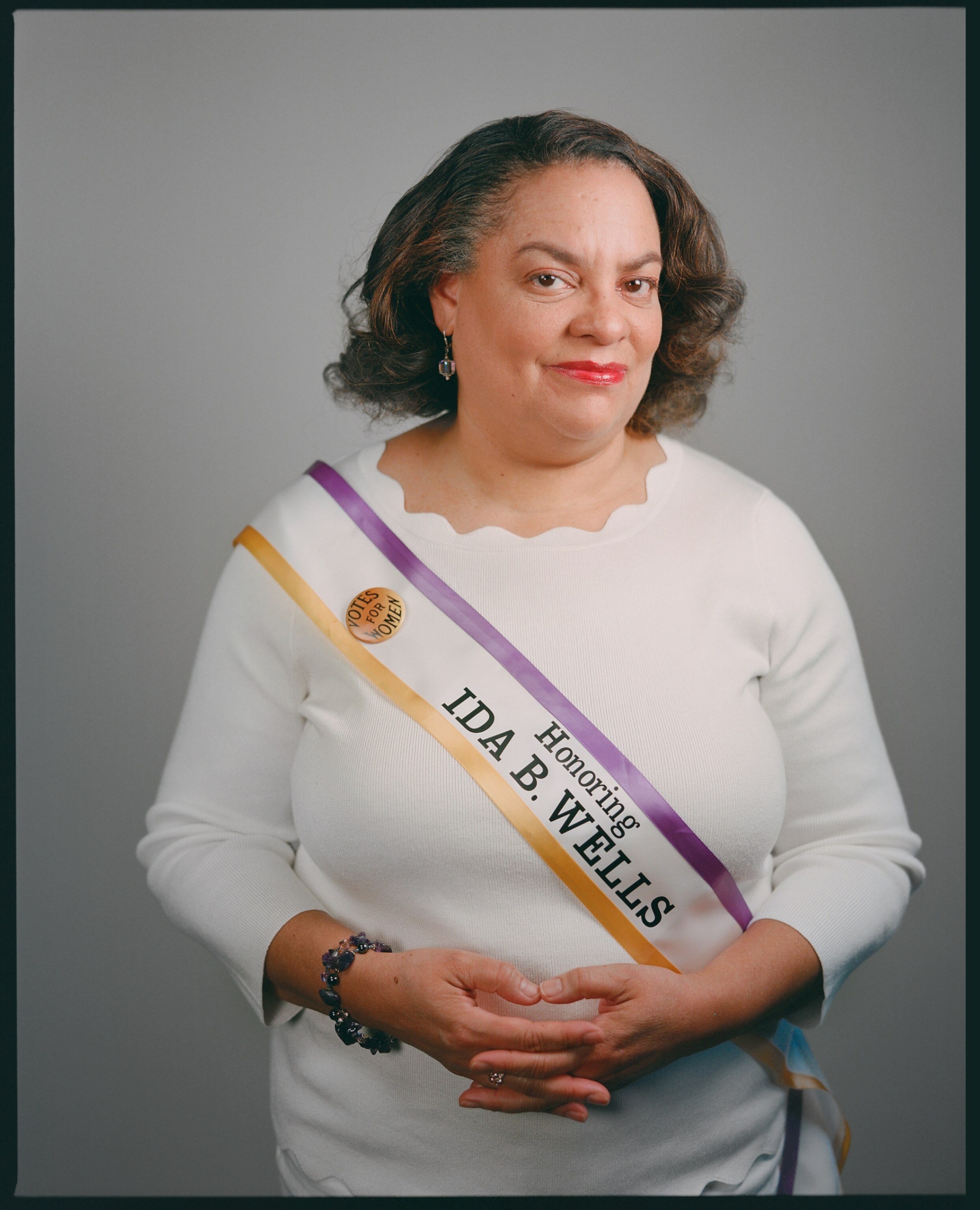 a woman wearing a purple and pink sash standing for a portrait