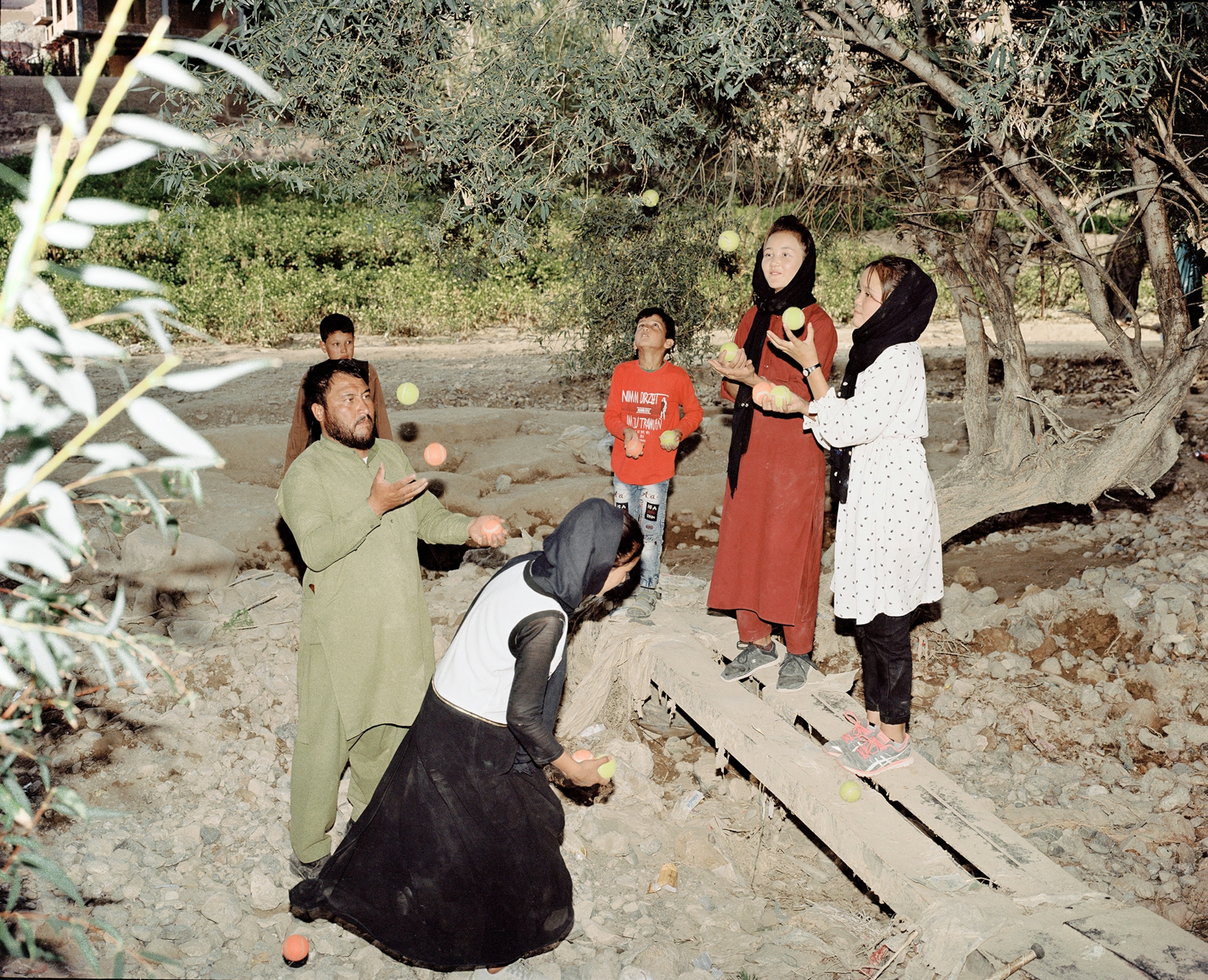 A group of Afghan girls and boys practice juggling with an adult teacher.