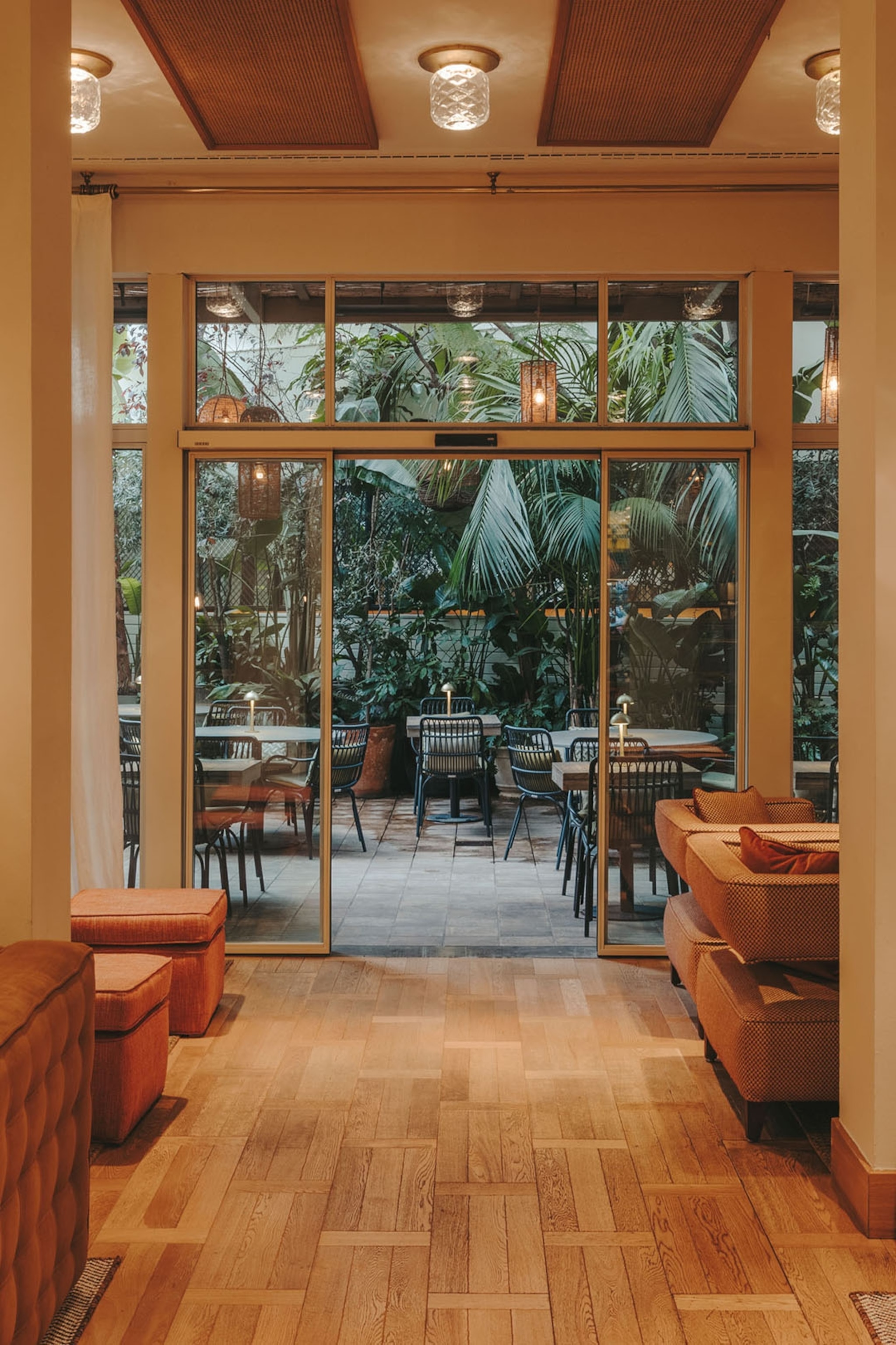 An airy, window-fronted hotel lobby leading out into a courtyard garden.