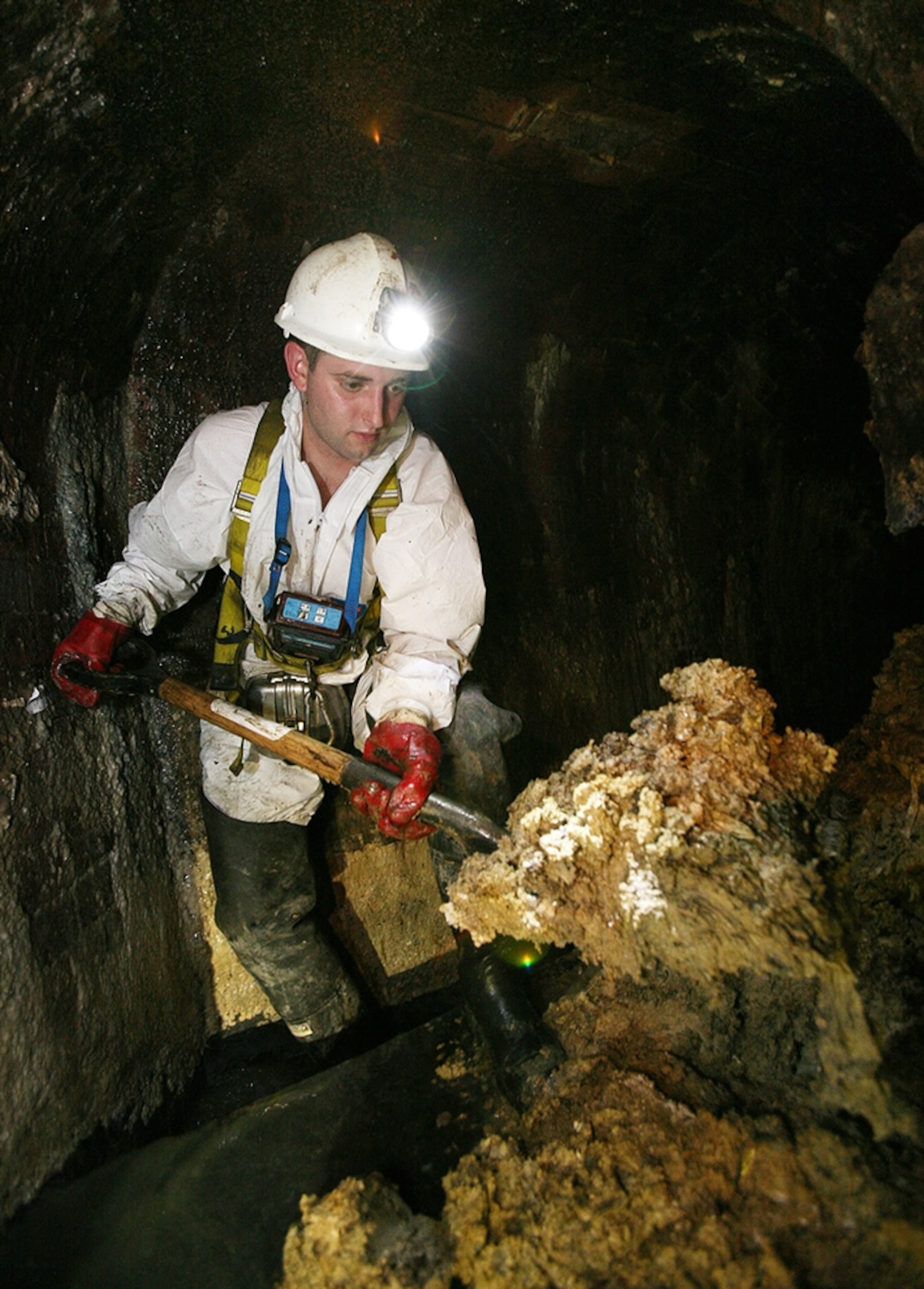 Picture of a "flusher" shoveling fat in a clogged sewer under Leicester Square in London