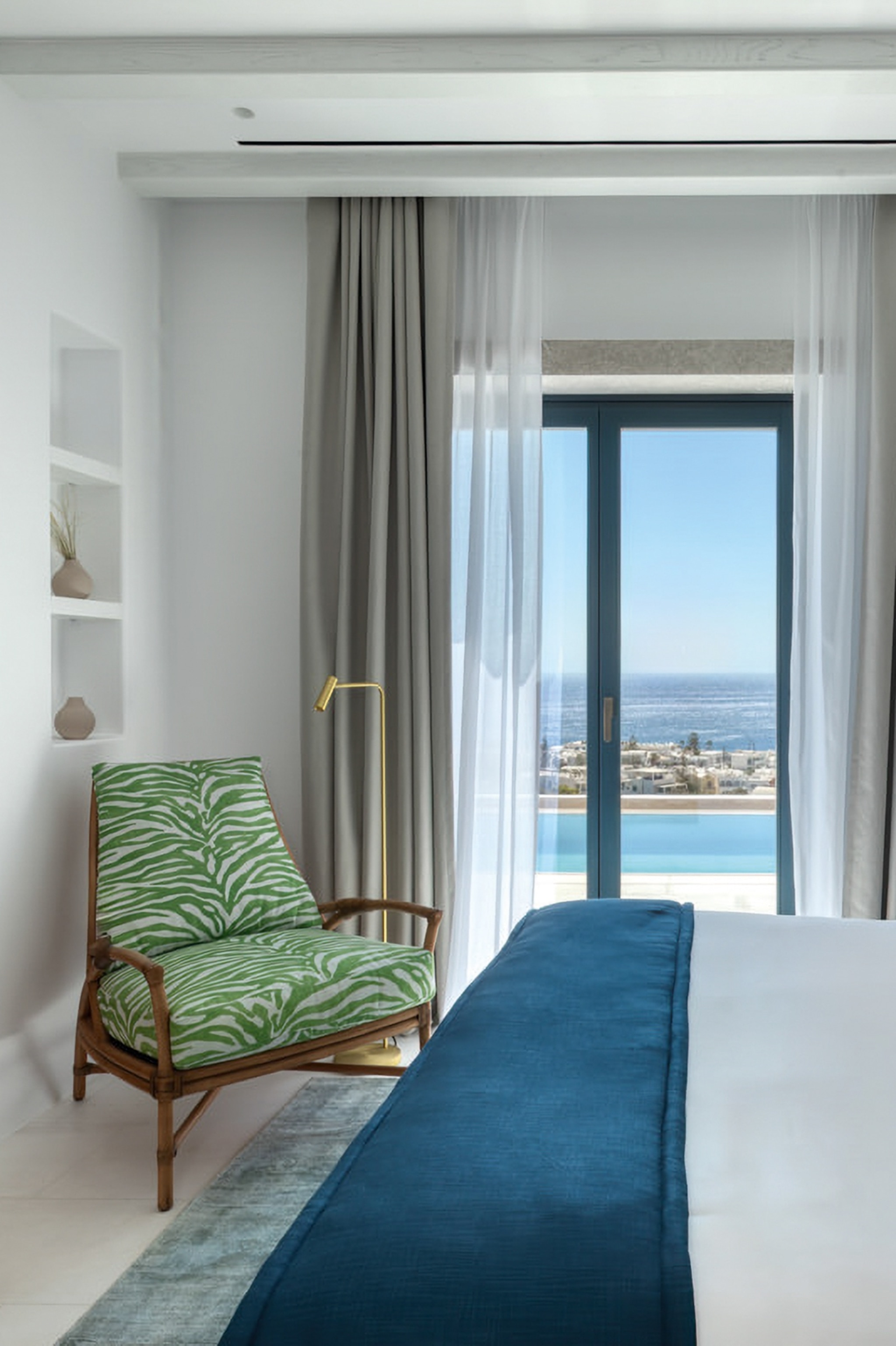 The interiors of a simple double hotel bedroom with views of the sea.