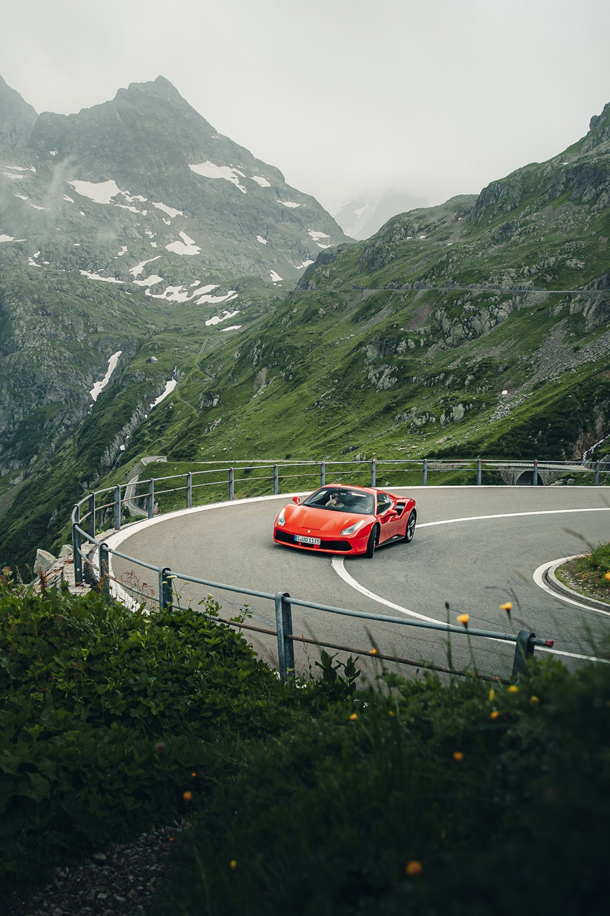 A Ferrari taking a curve on a mountain pass in Switzerland.