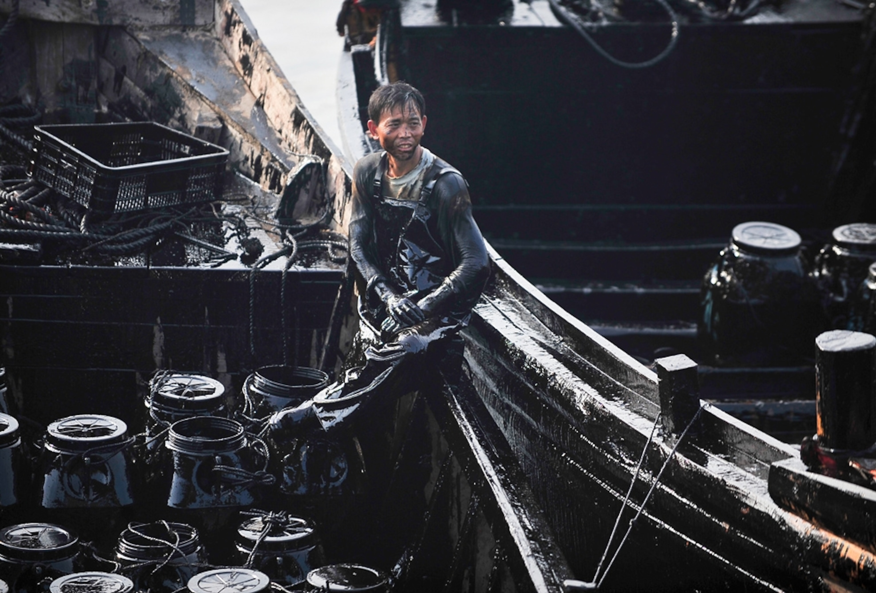 Picture of fisher assisting with the cleanup of the China oil spill.