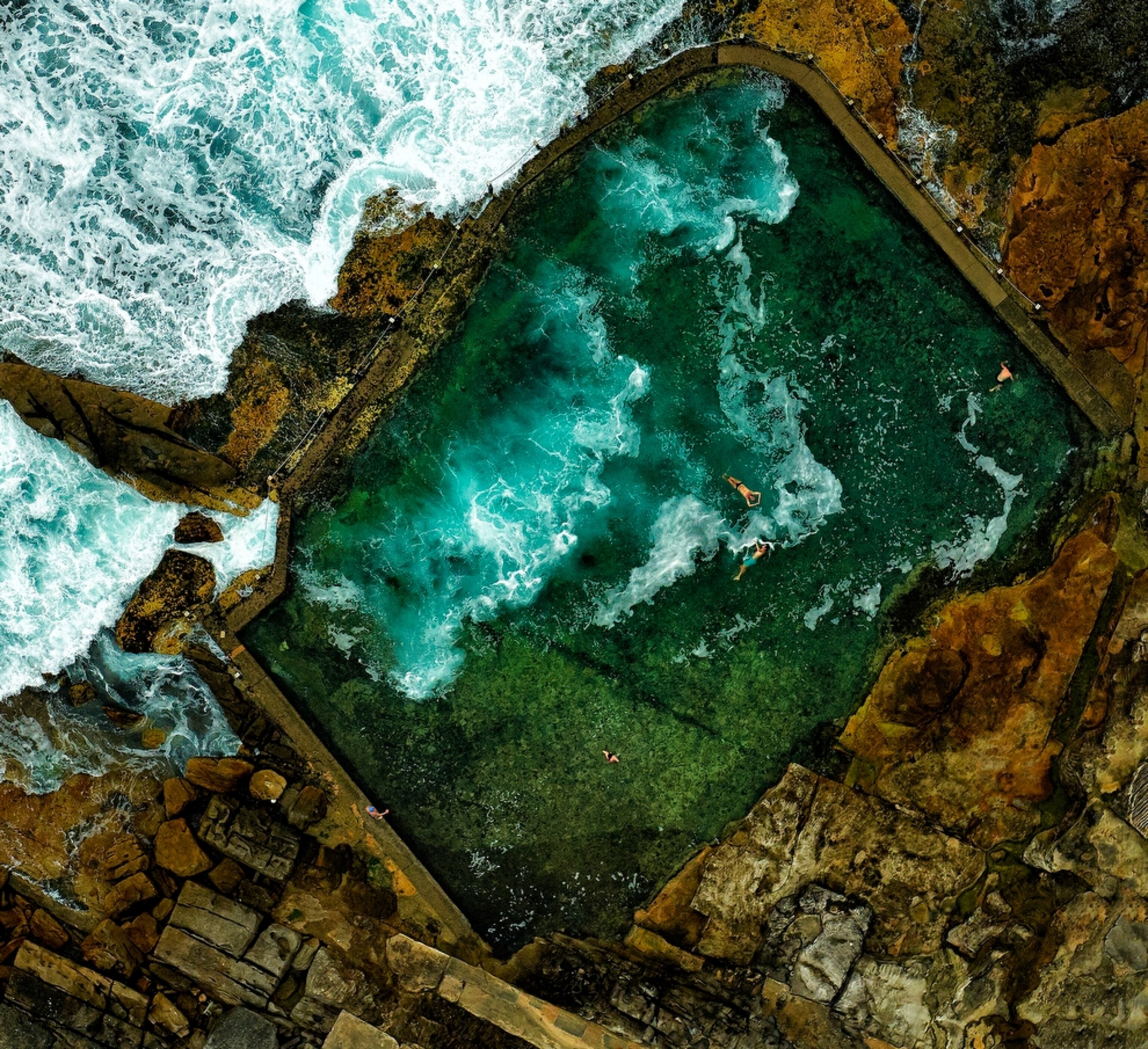 people swimming in a rock pool on the coastline near Sydney, Australia.