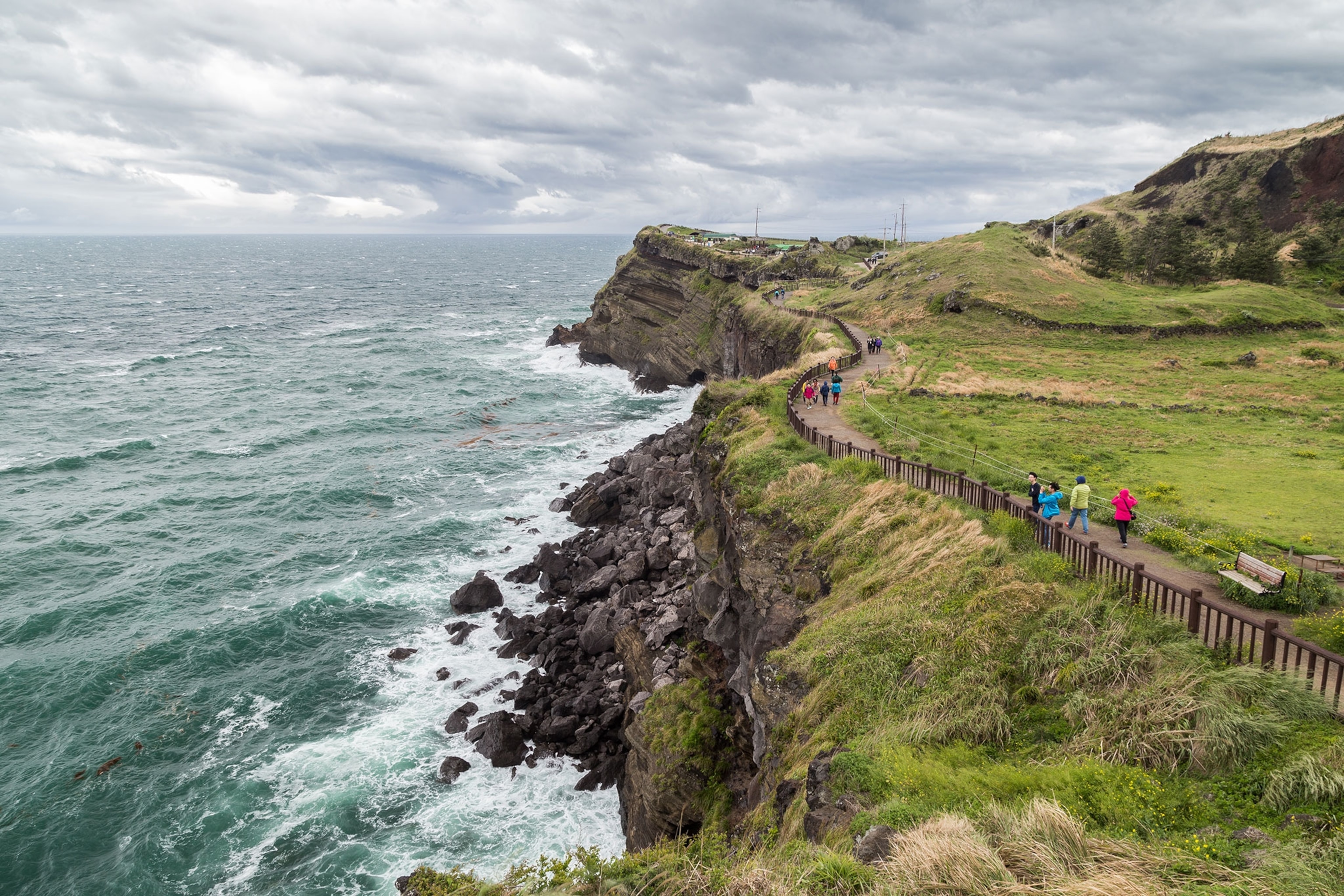 View of people and steep and rugged cliff next to the Songaksan Mountain on Jeju Island in South Korea.