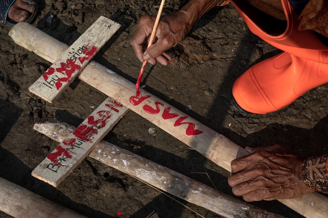 Man writes his relative's name on a temporary grave marker.