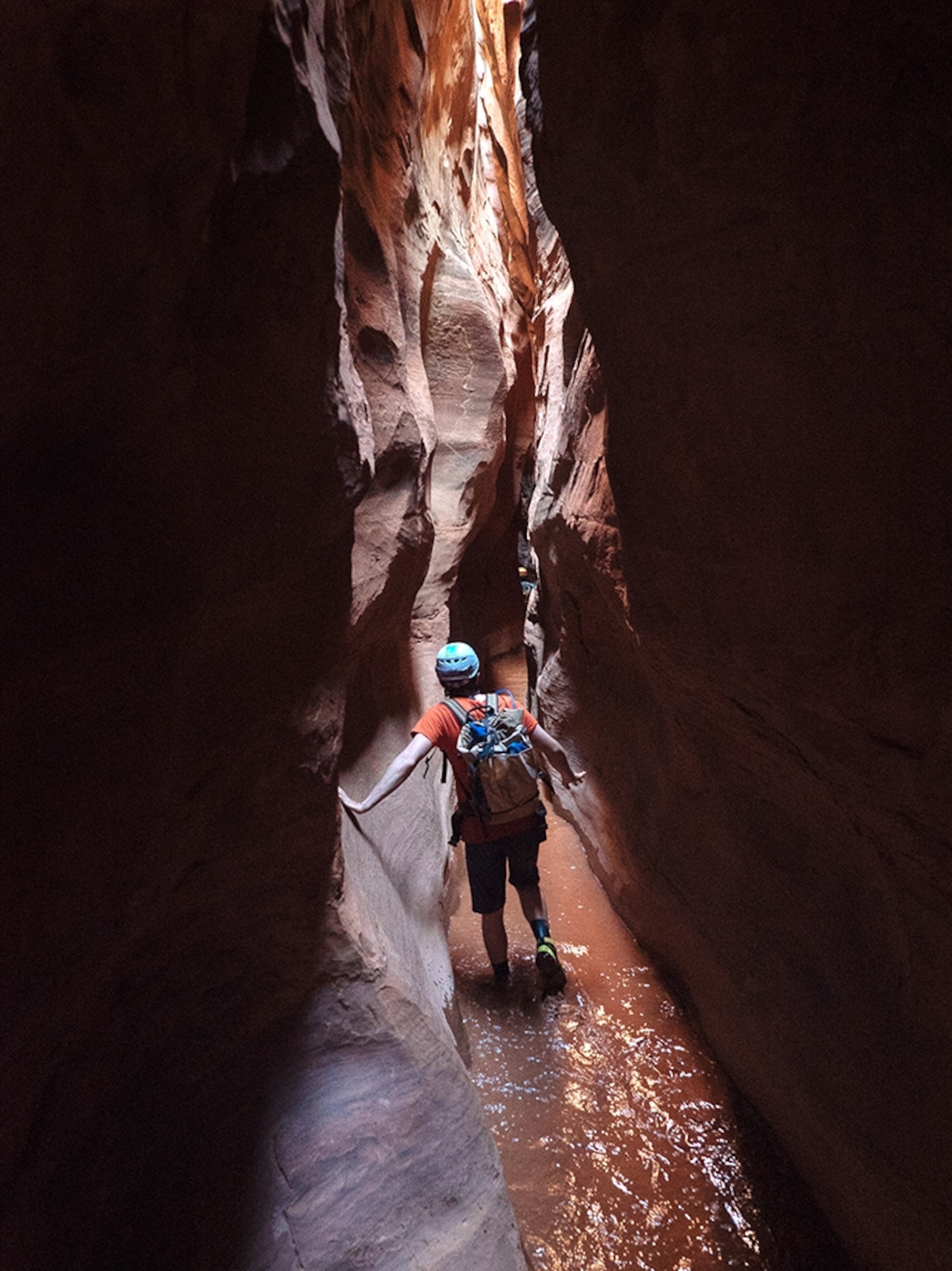 a man walking through a steep creek ravine in Utah.