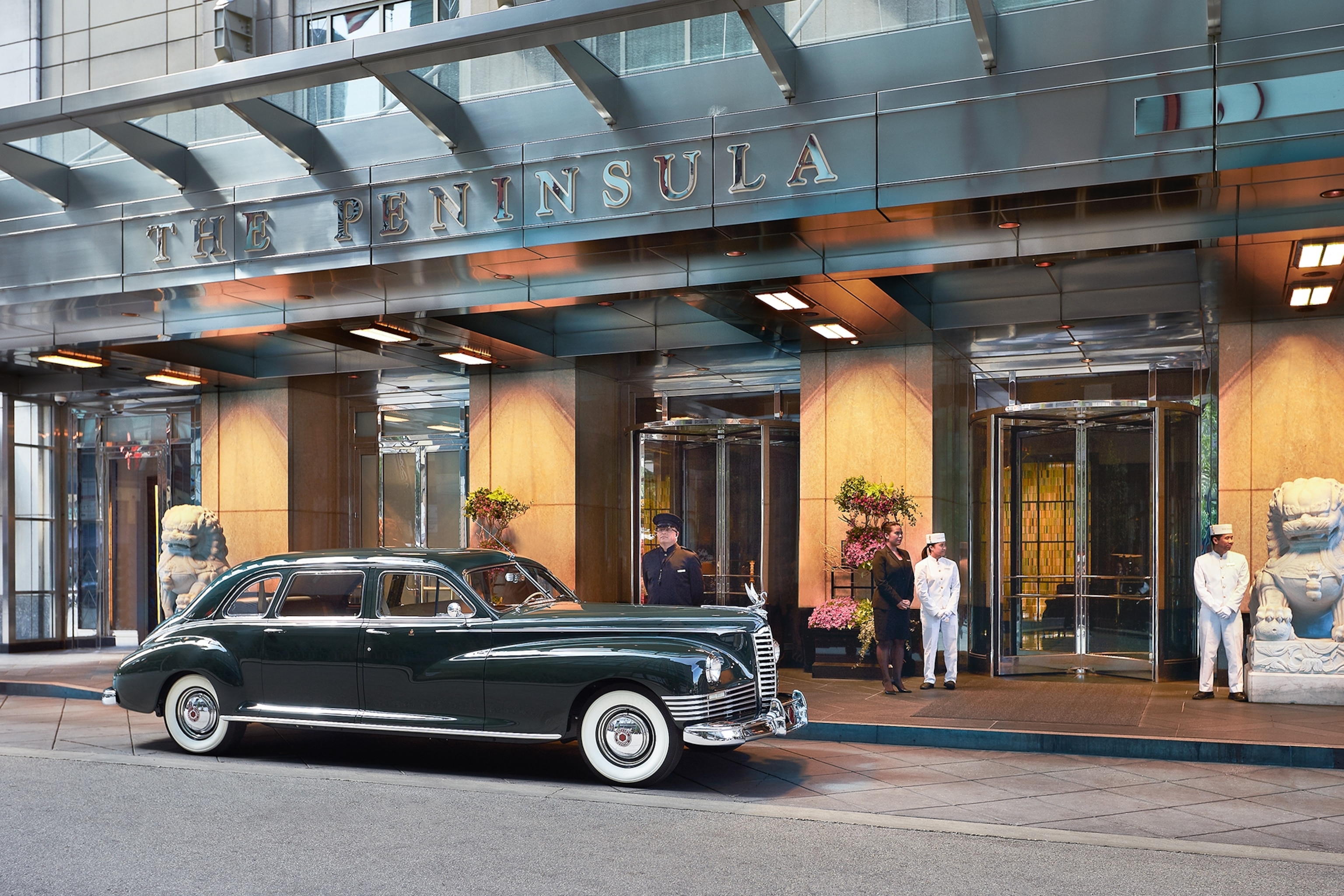 The front of a hotel with a car parked up.