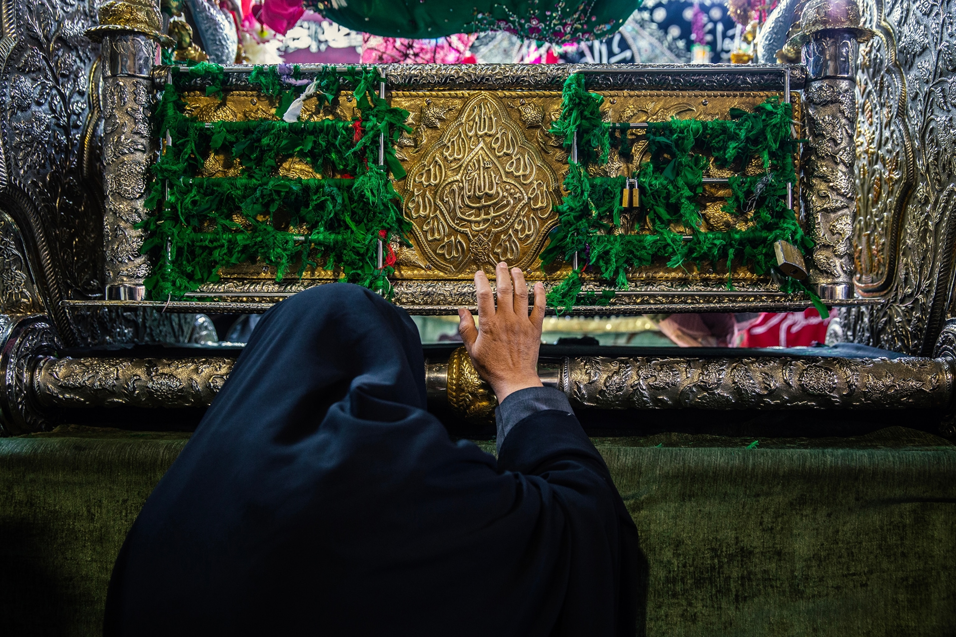 A woman holds her hand up to an alter tied with green cloth