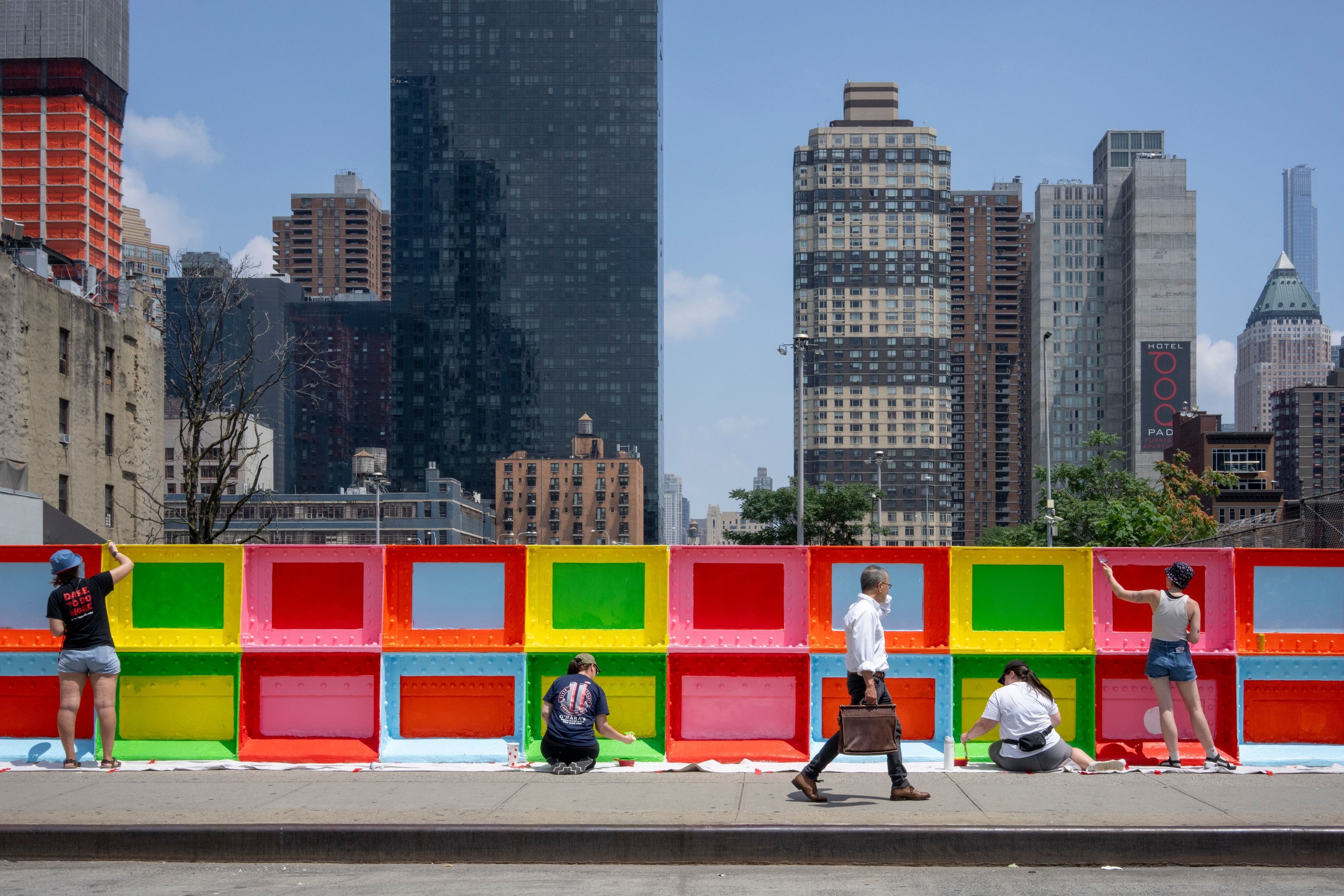 People walk past a colorful wall in NYC