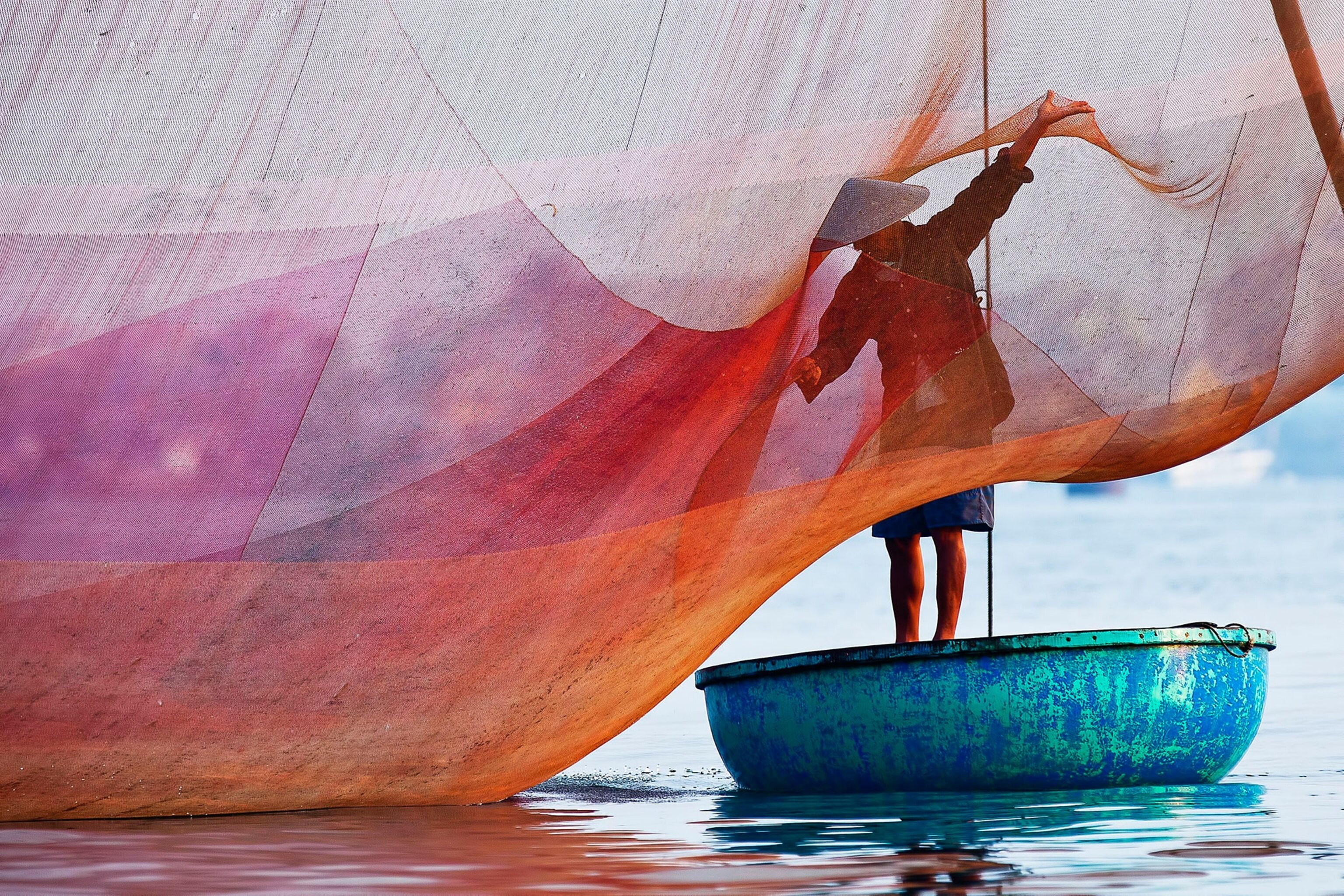 a fisher engulfed by colorful fishing net