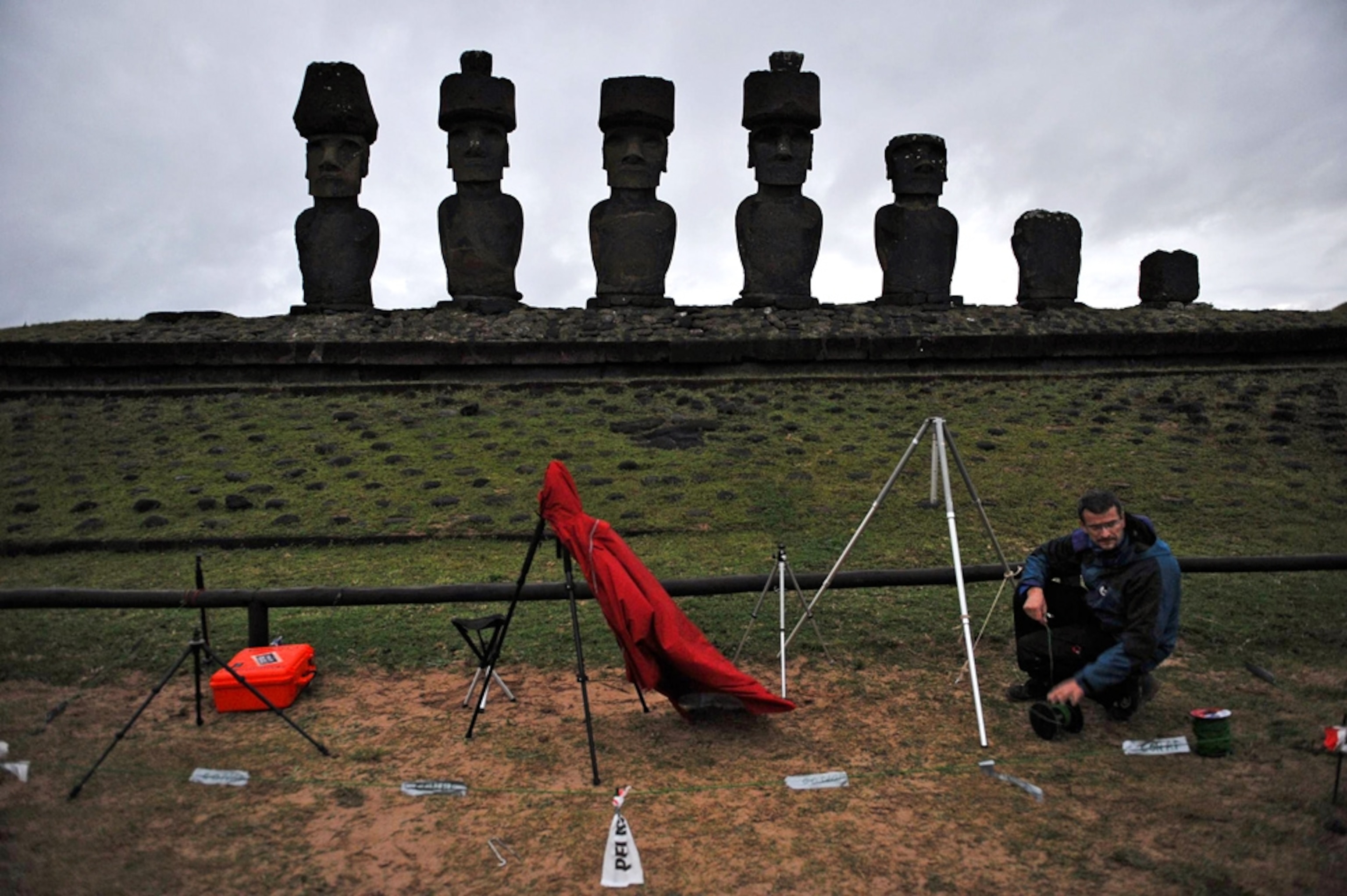 Picture of a photographer setting up equipment near a line of stone statues on Easter Island.