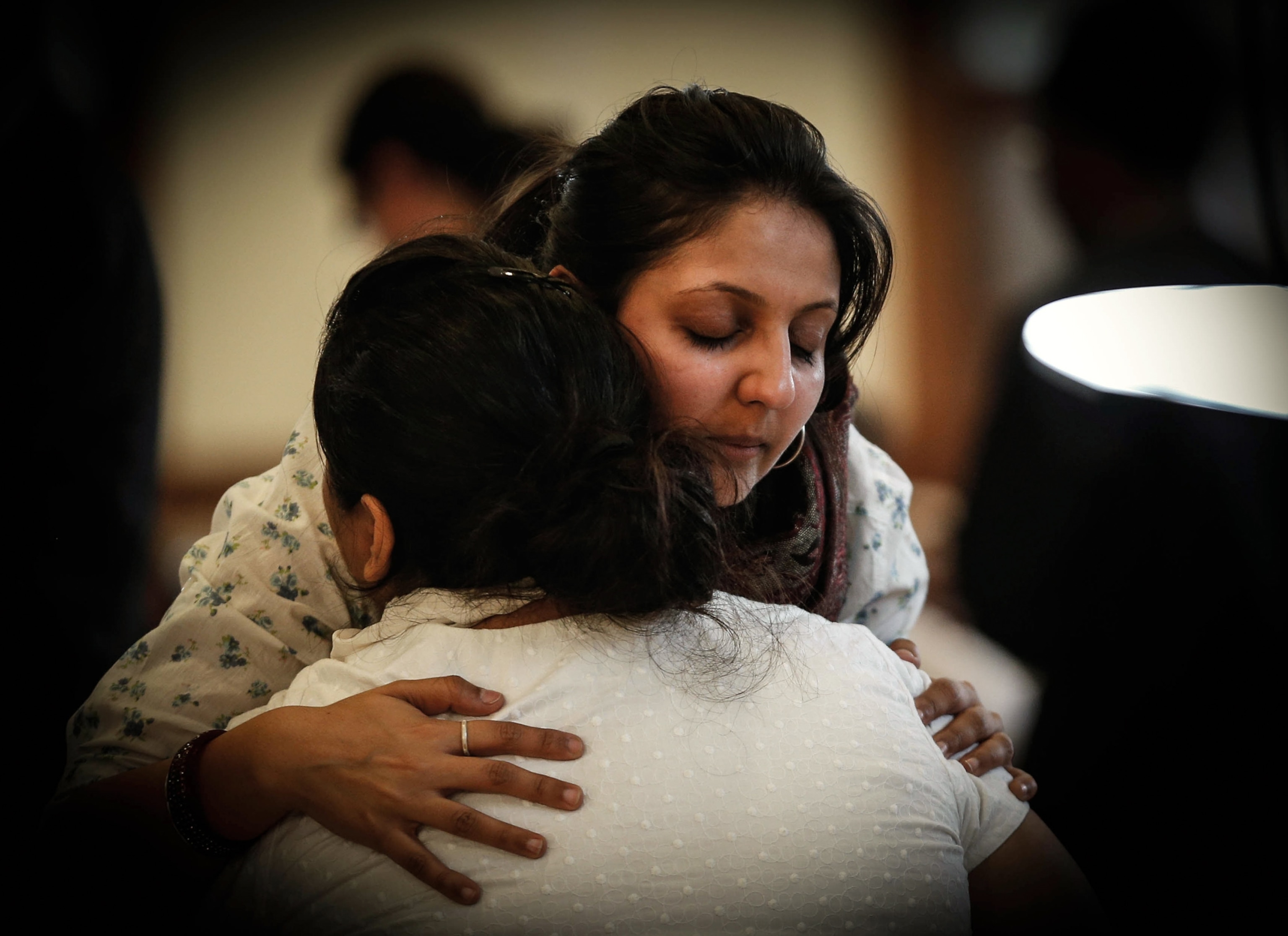 A visitor hugs a relative of Mitul Shah during his funeral.