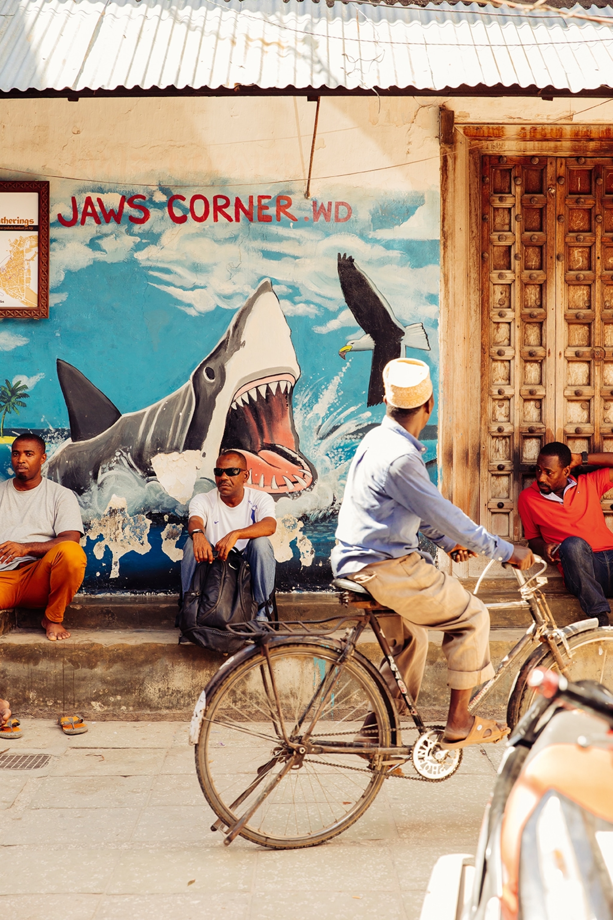 A busy, urban scene showcasing a bright and lively mural as passengers walk or cycle past.