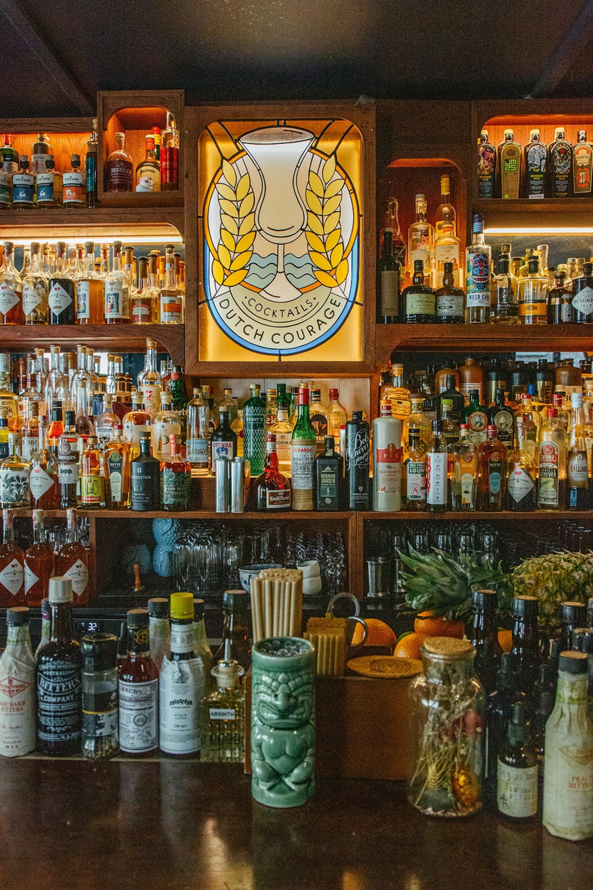 A well-stocked bar with multiple shelves and rows of alcohol bottles illuminated from behind.