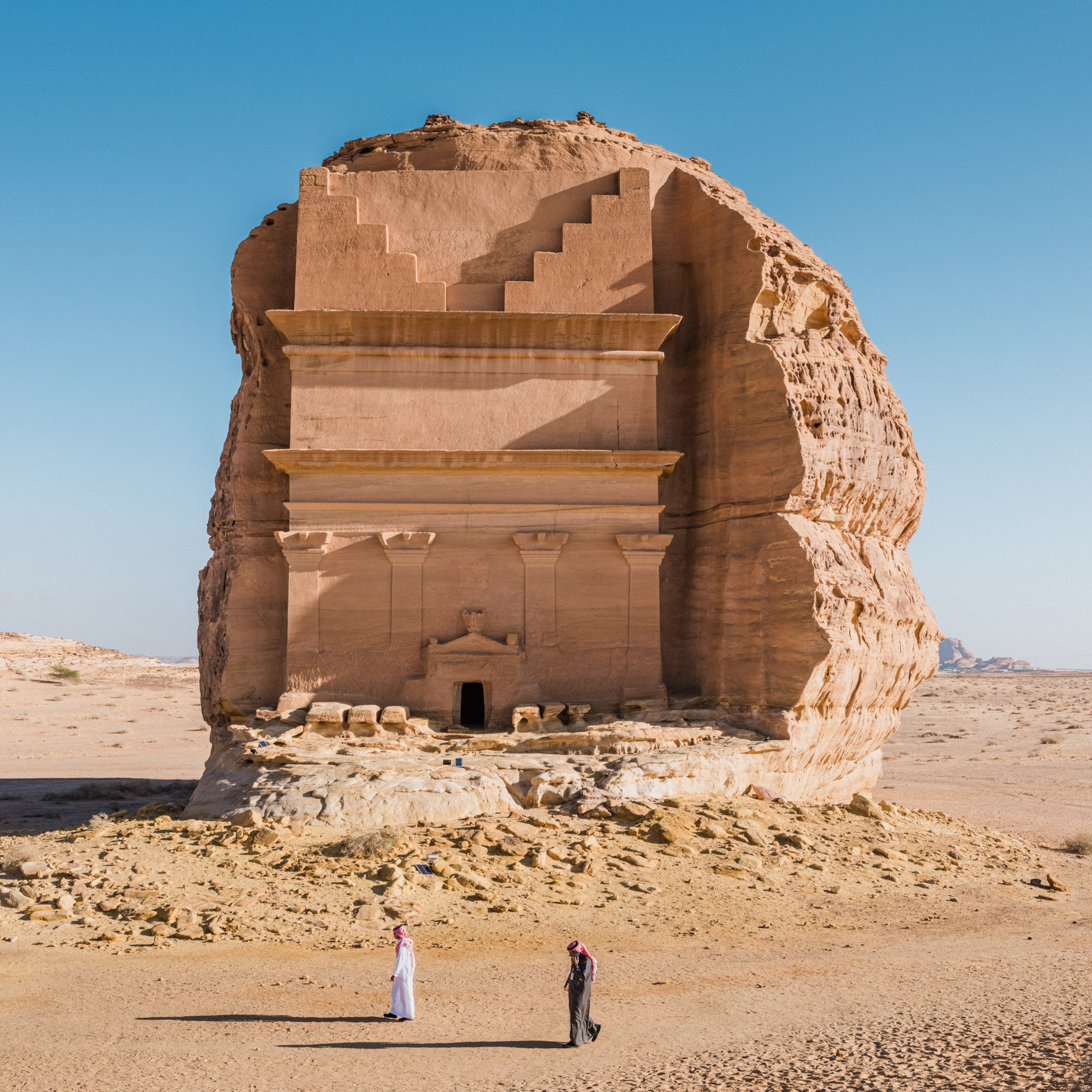 Two men walk in front of Qaṣr al-Farīd, or "the Lonely Castle," in Mada'in Saleh, Saudi Arabia. The structure is the largest and one of the best-preserved out of more than 100 tombs on the site, all of which date from approximately the 1st century BC to the 1st century AD during the pre-Islamic Nabataean Kingdom. In 2008, Mada'in Saleh—also known as Hegra or Al-Hijr—became Saudi Arabia's first UNESCO World Heritage Site.