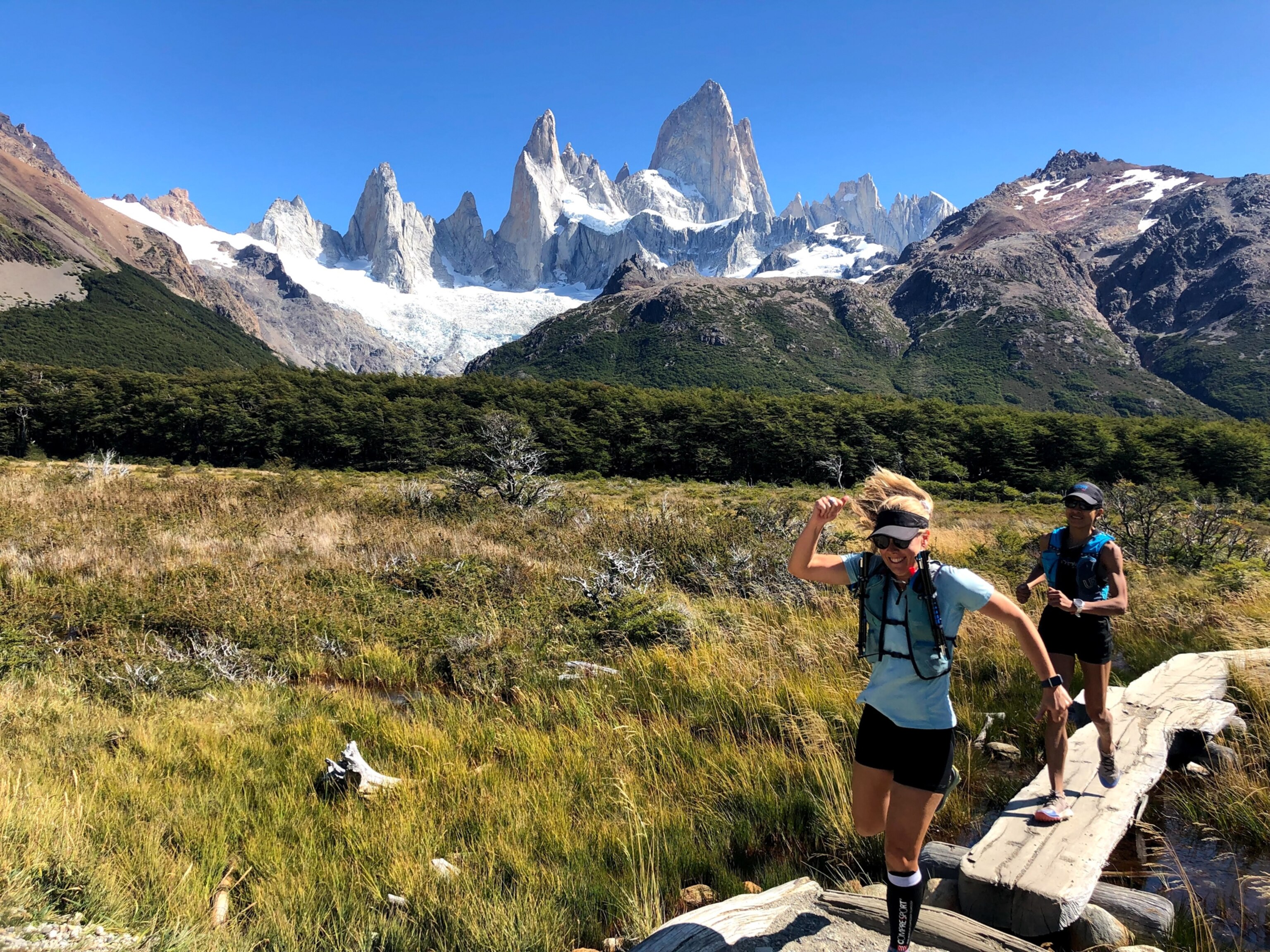 Smiling runners with jagged, white mountains in the background
