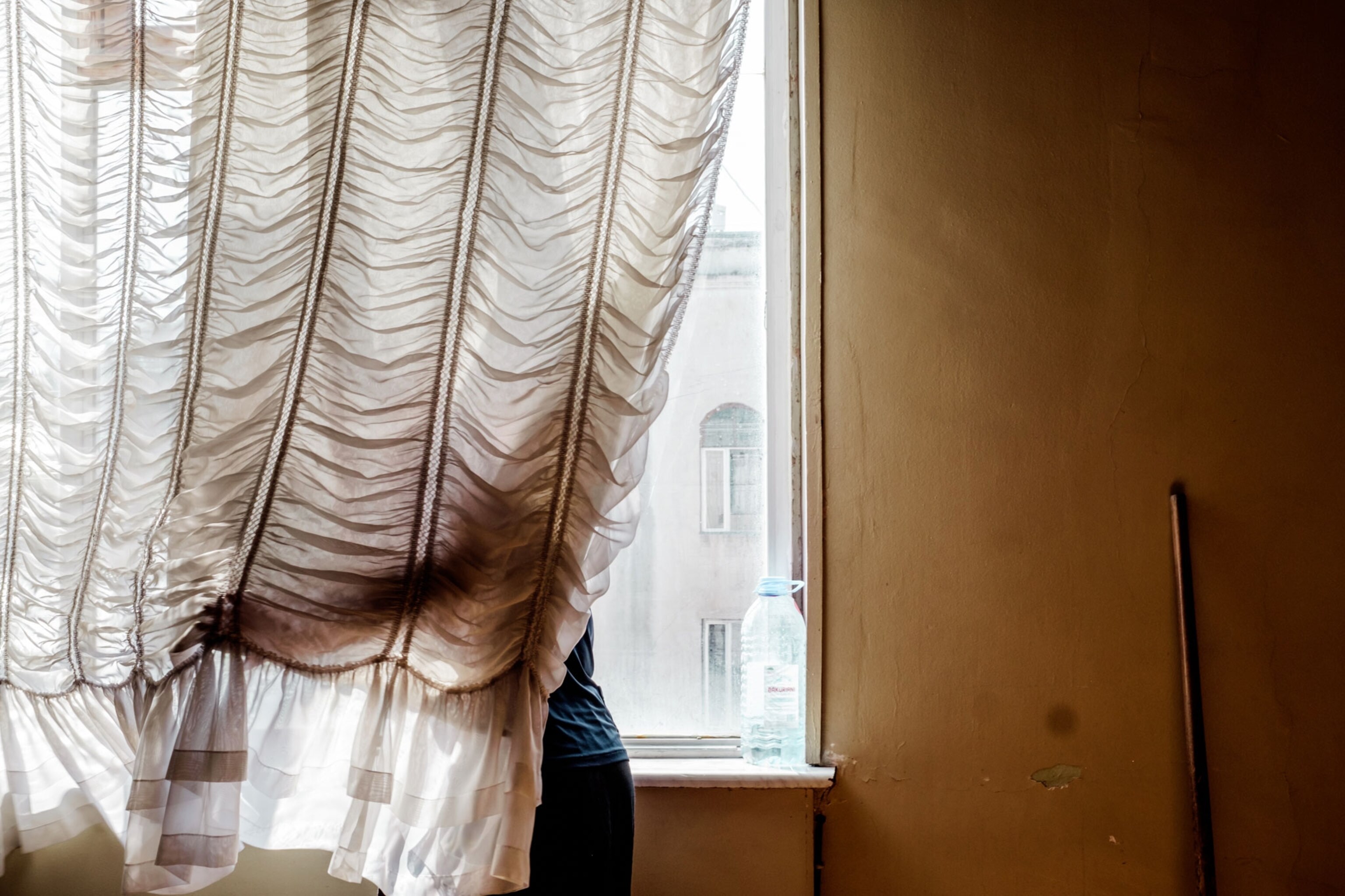 Nana, 58, cleans behind a curtain on the top floor of Hotel Georgia