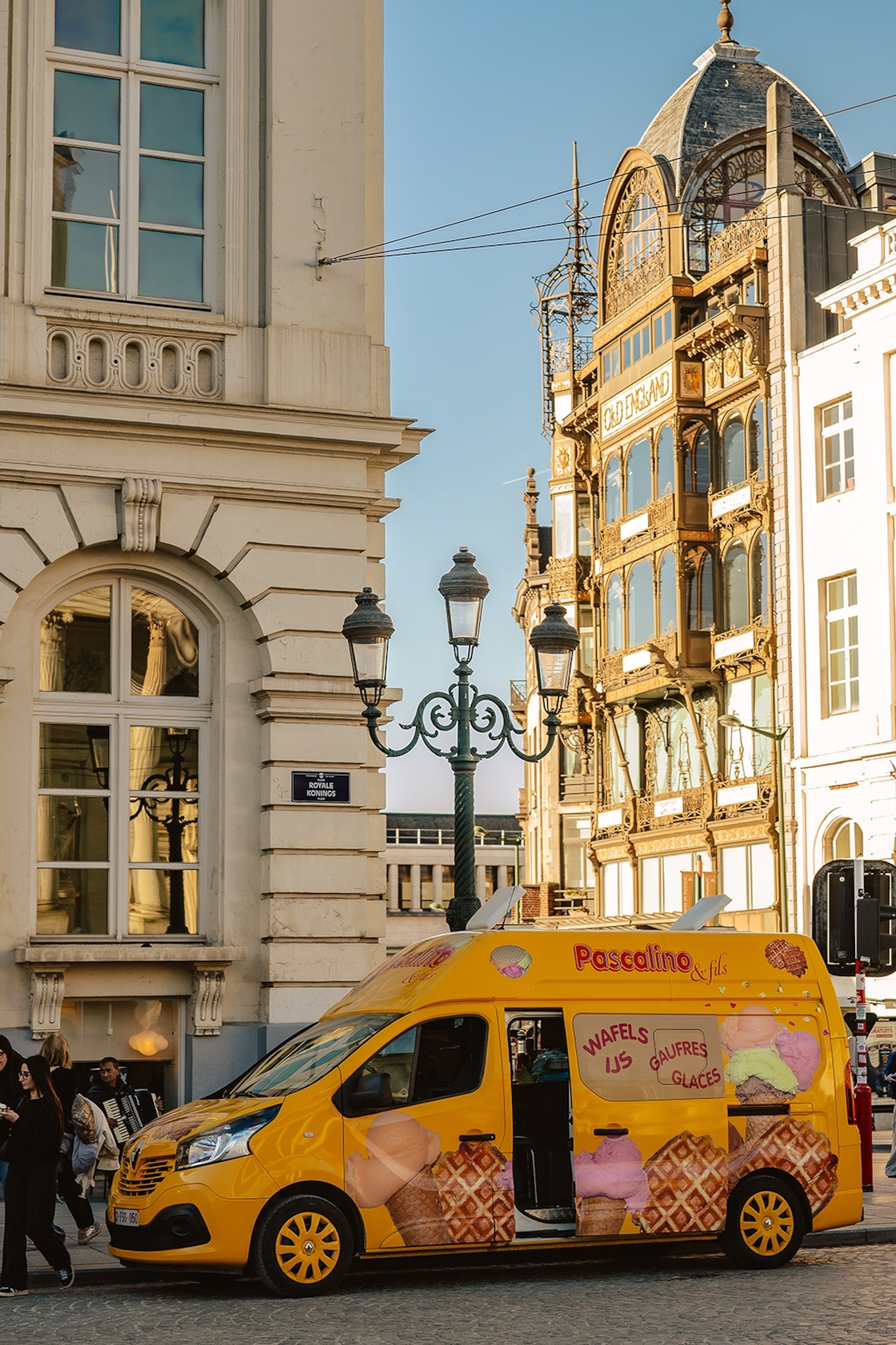 Street view of buildings and a van on a sunny day.