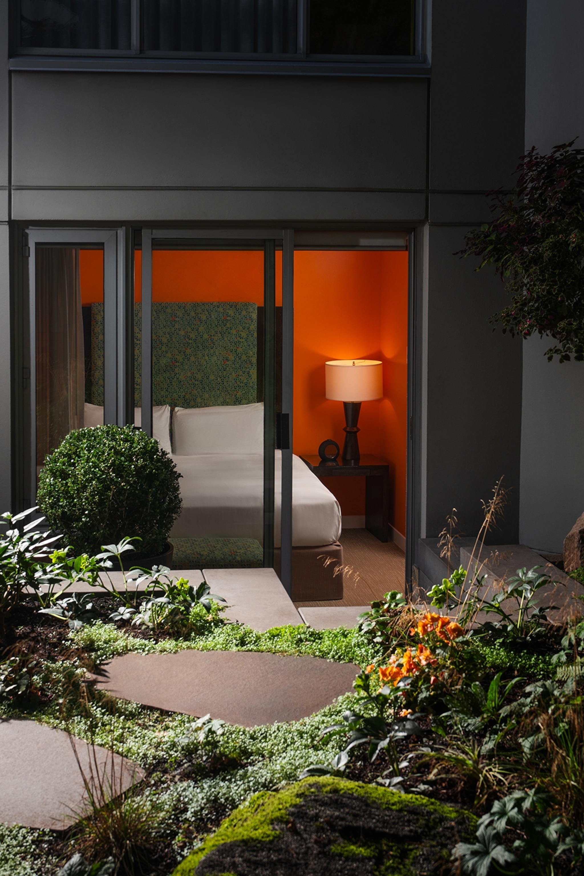 The backdoor of a hotel room leading into a secret garden with rock tiles to walk on.