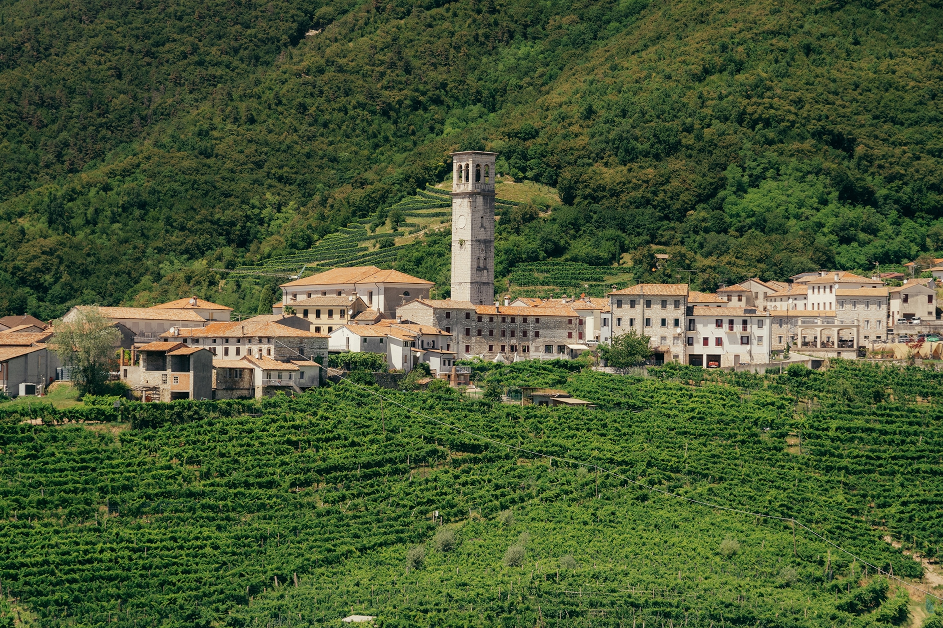 A rural village with a stone church tower in the middle of lush hills.