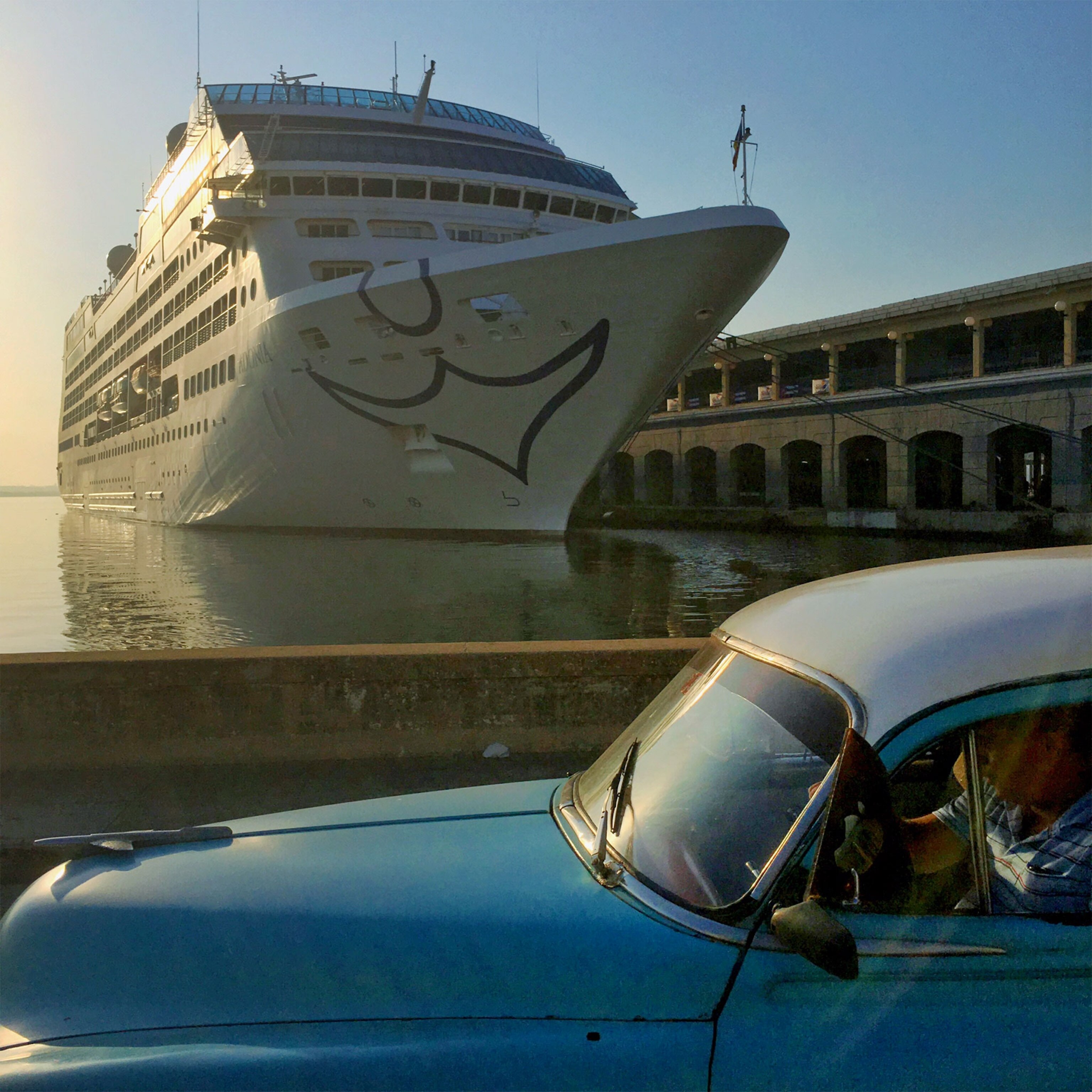 a car passing a cruise ship in Havana, Cuba