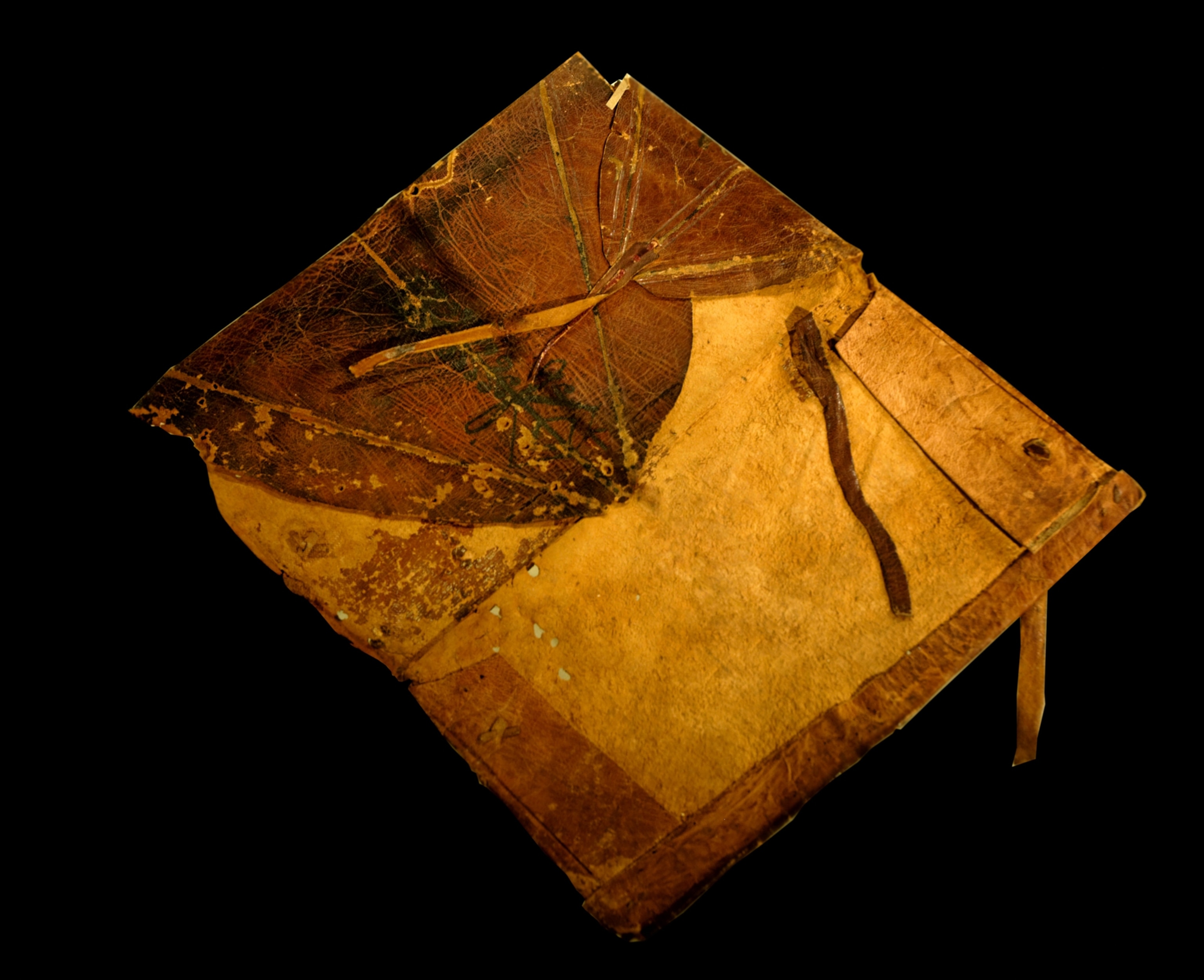 Old leather-bound book with a worn cover, frayed edges, and tie closures, set against a black background