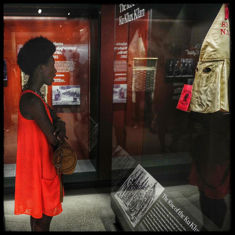 A woman gasps after staring into the mask of a Ku Klux Klan member on display at the museum.