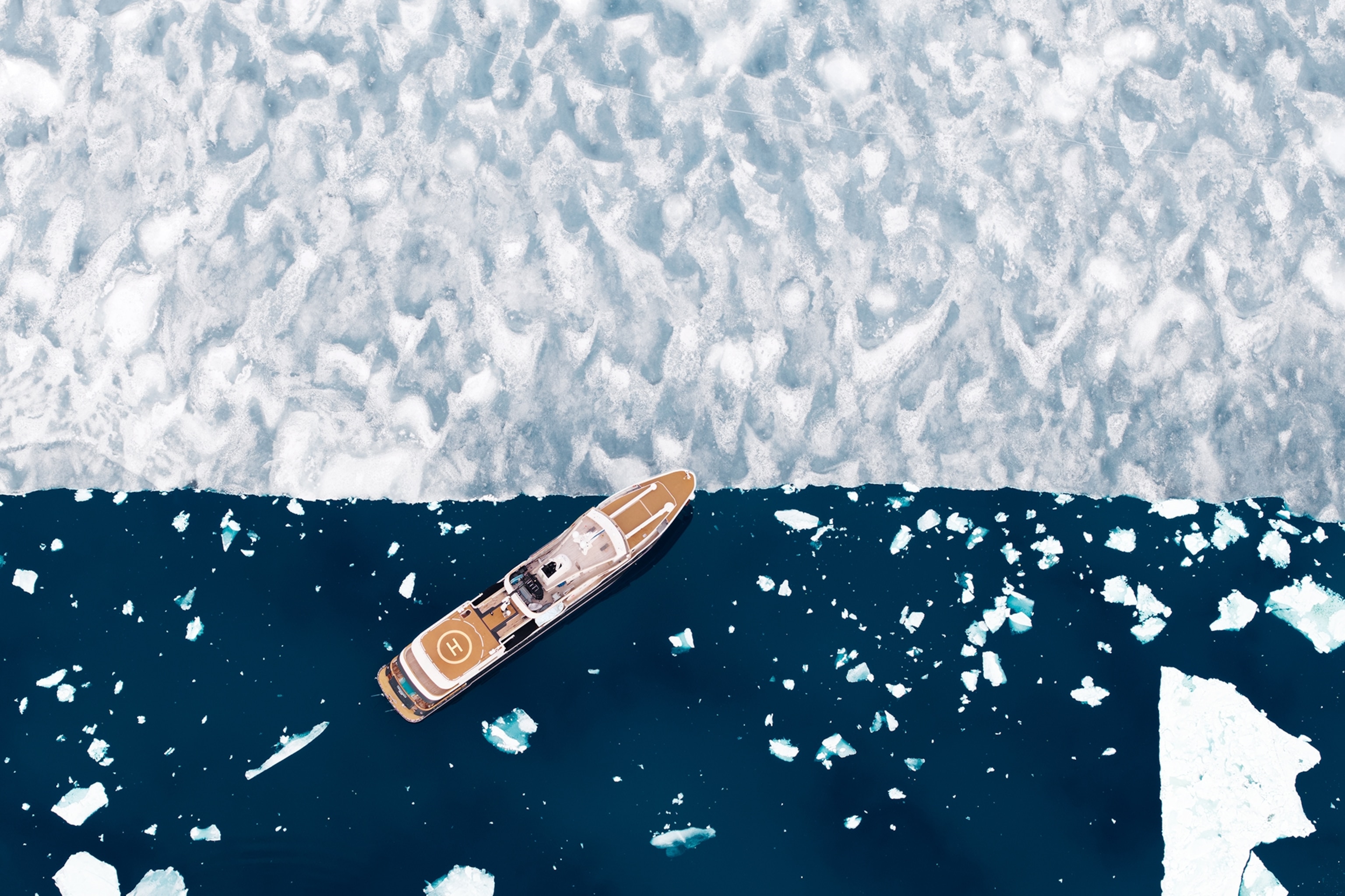 A cruise ship shot from above as it's docked at the edge of an ice cap.