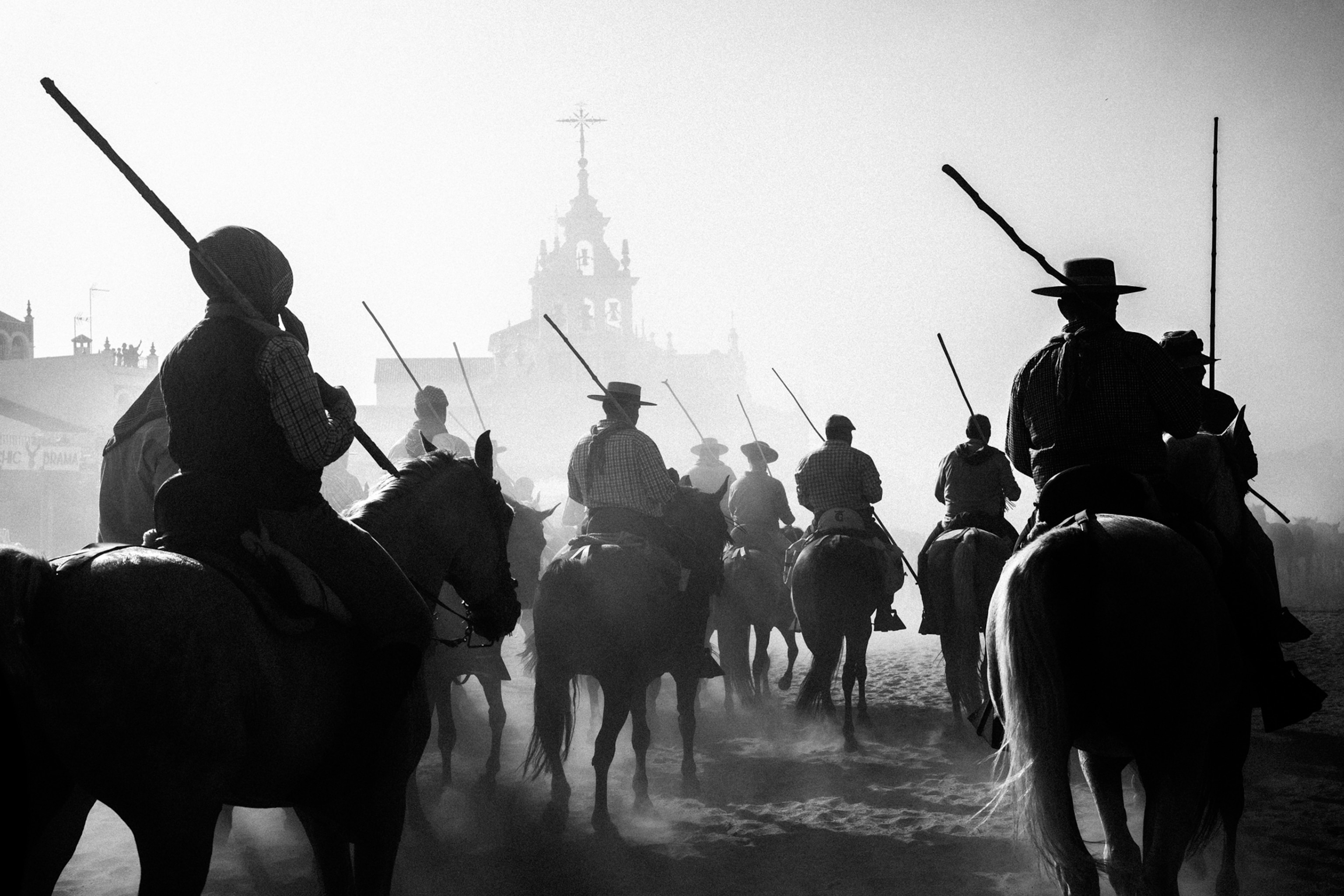 People on horses ride toward a church