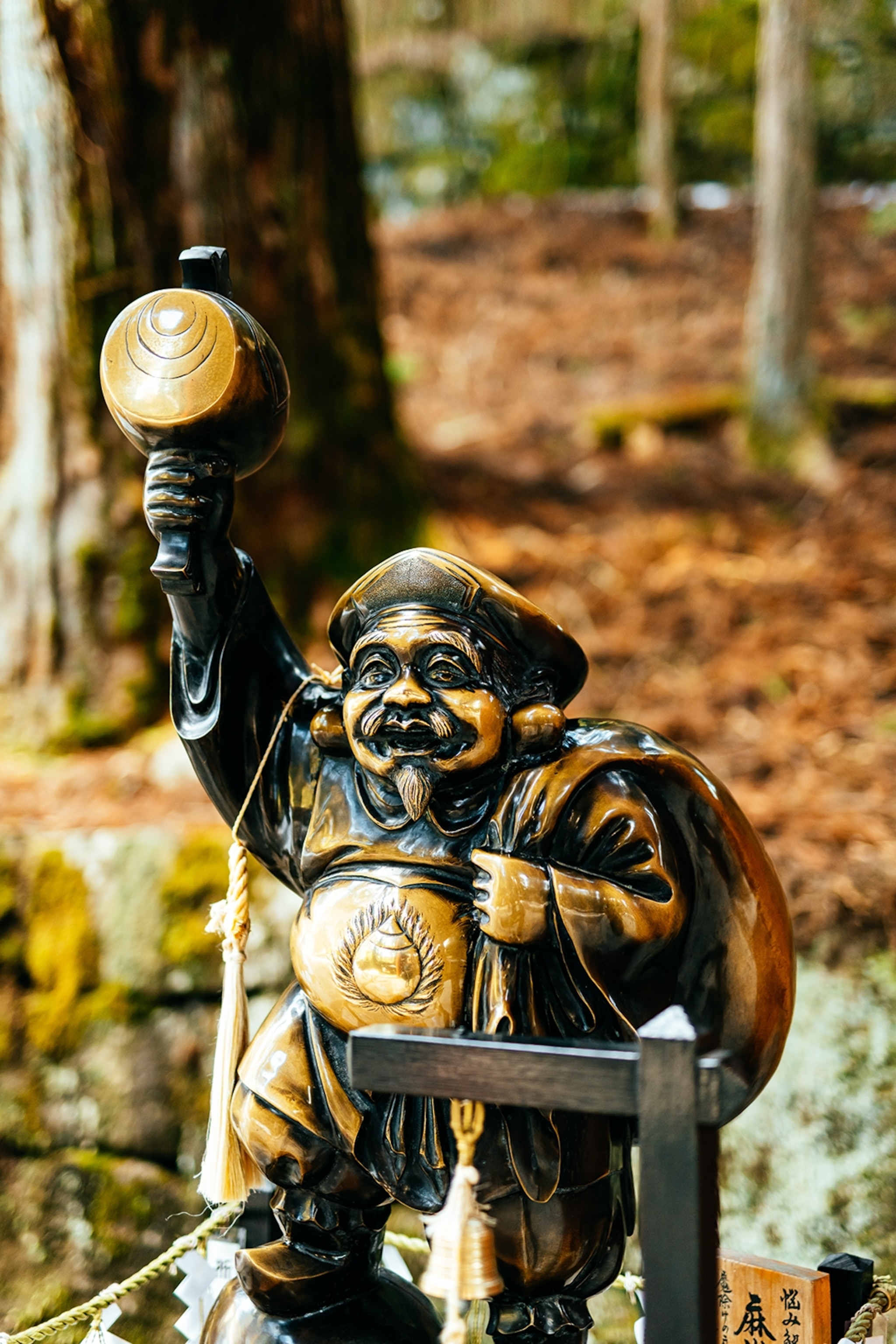 A close-up of a buddha-like bronze statue holding up a round tool.