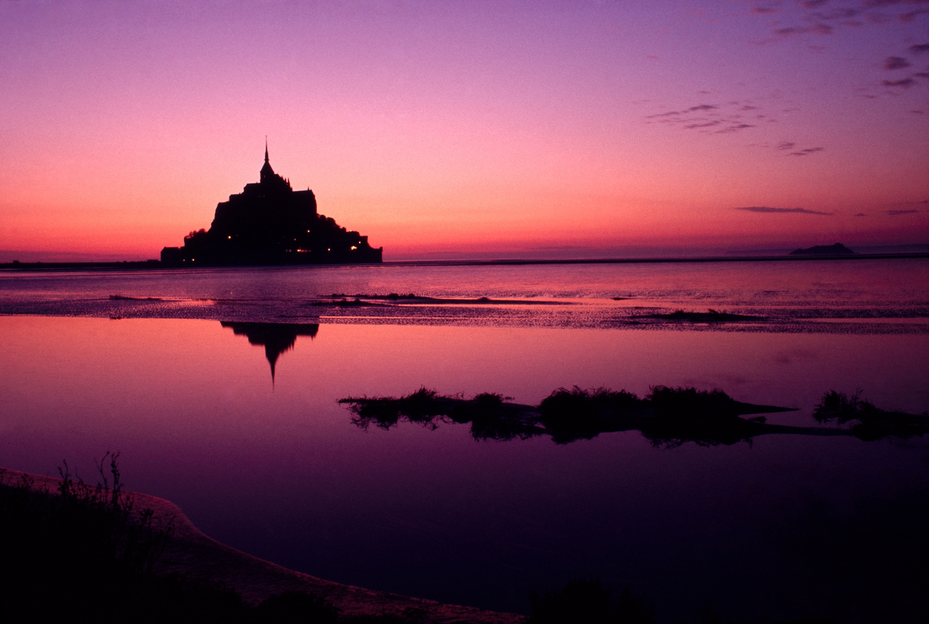 Twilight view of abbey and its town across bay.