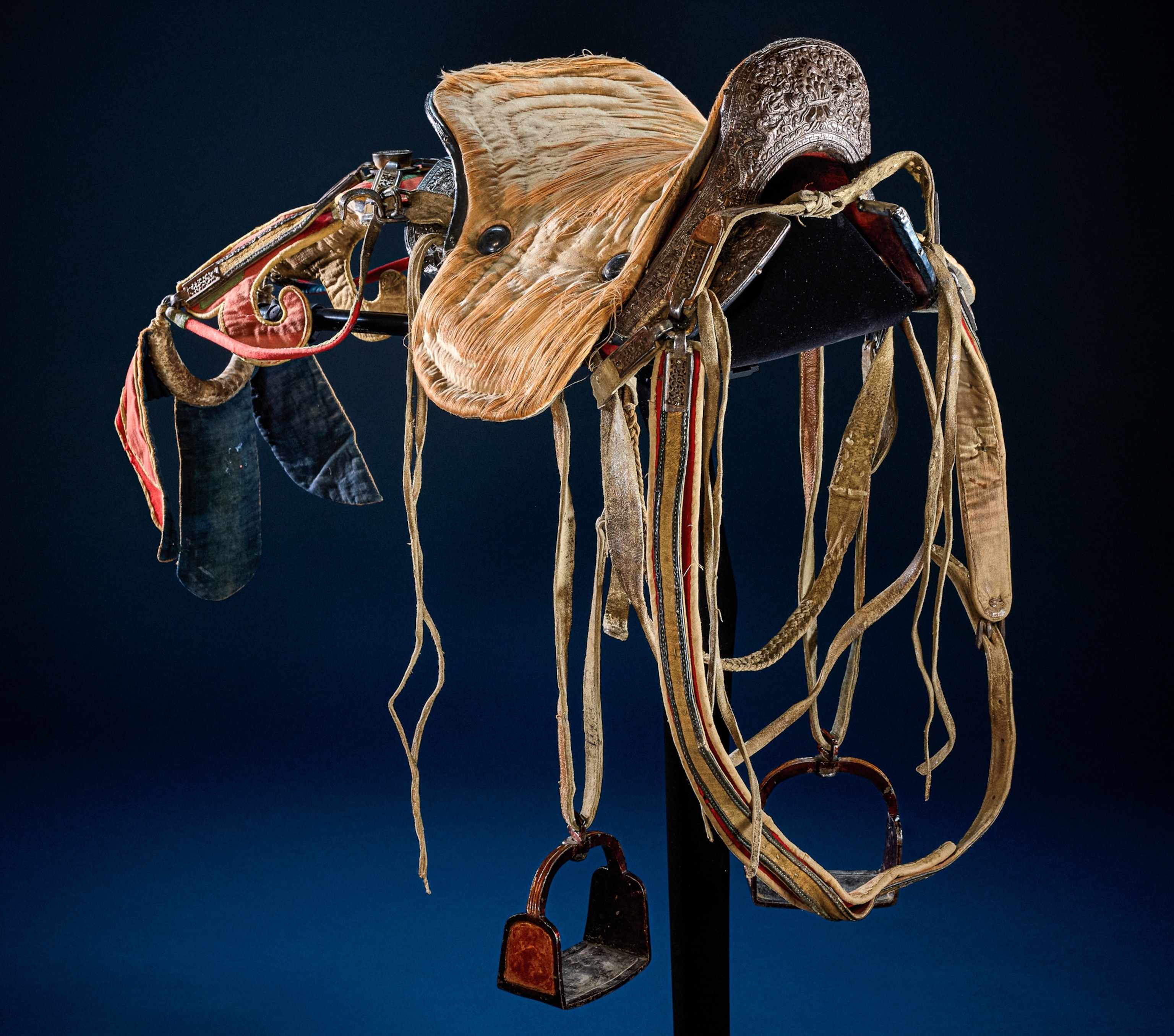 Saddle with stirrup leathers and stirrups. Silk seat with cotton backing. Leather tail ornaments.