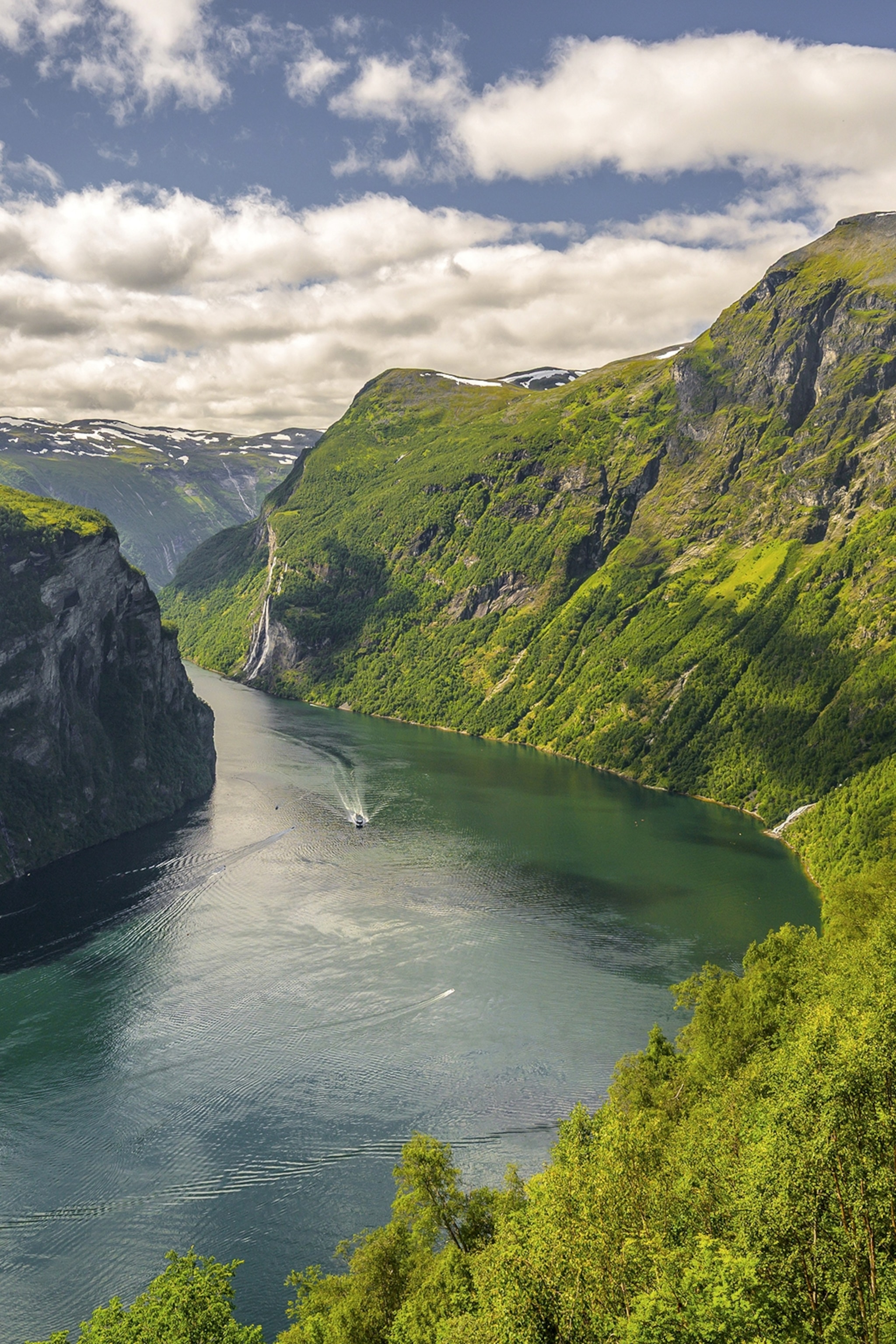 A river coursing through a mountain valley with a boat navigating its way downstream.