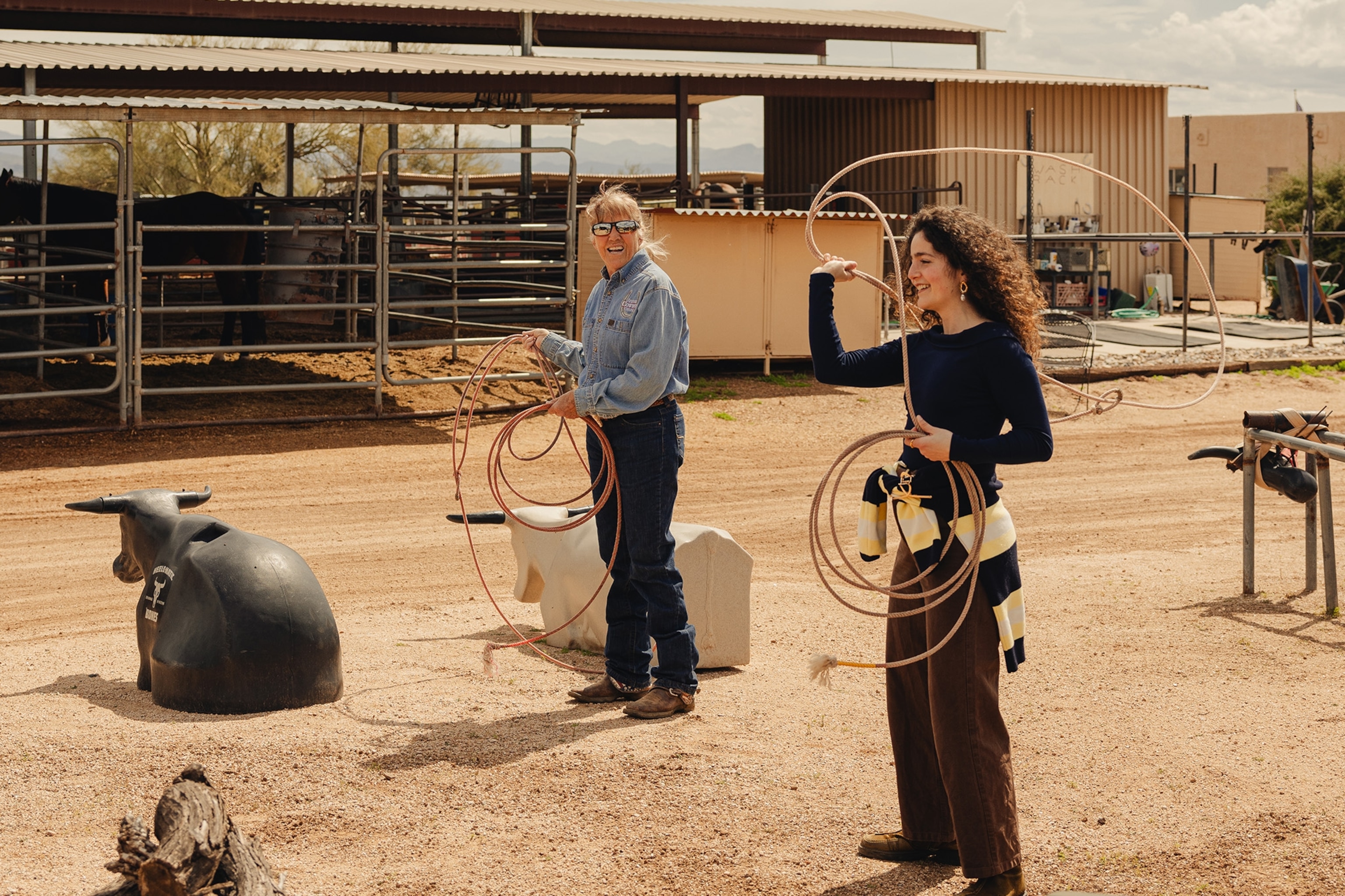 Wrangler teaching someone how to swing a rope on a ranch