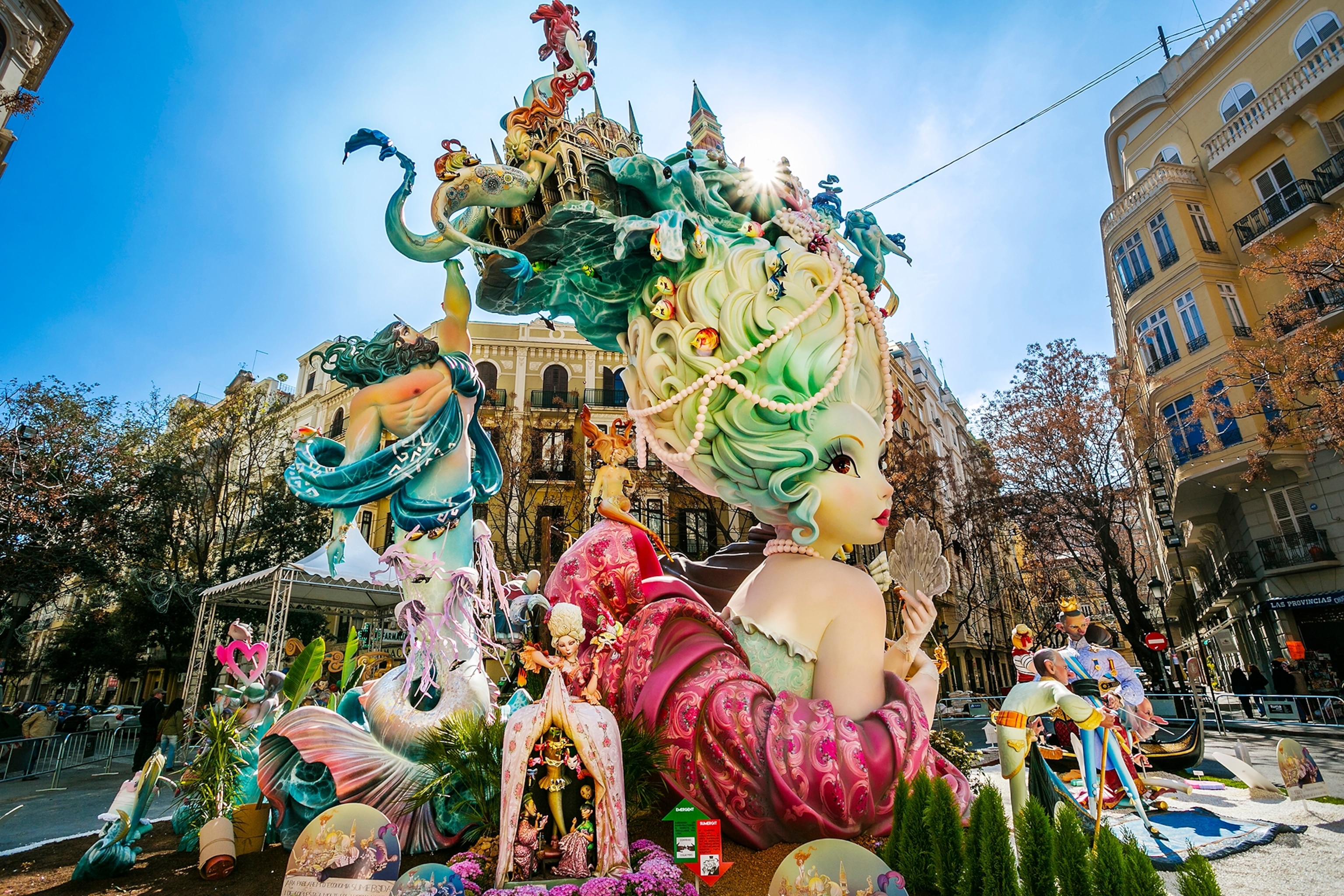 A decorated float with towering figures as it heads down a boulevard.