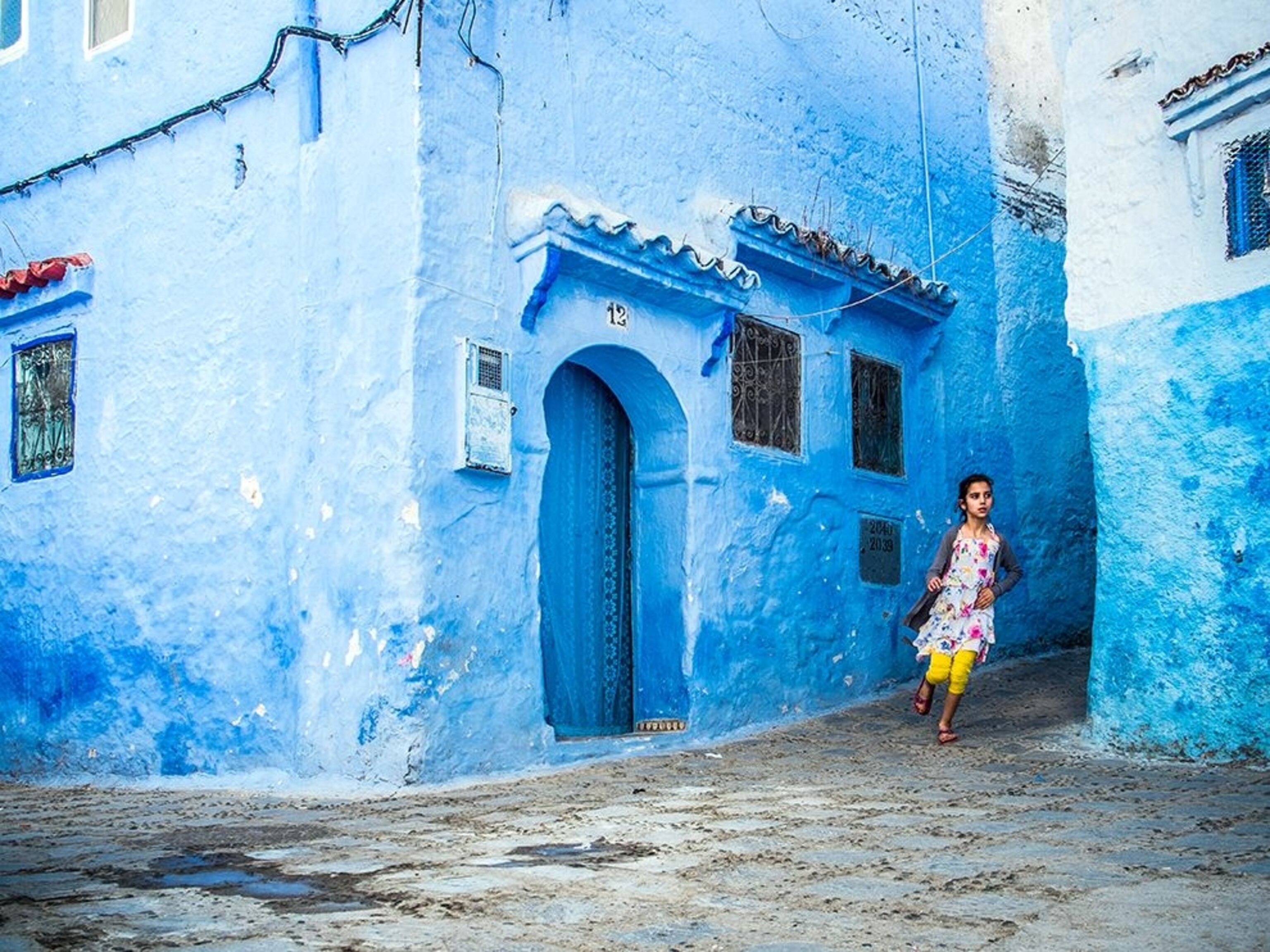 a girl running in the blue lanes of Chefchaouen Medina, Morocco