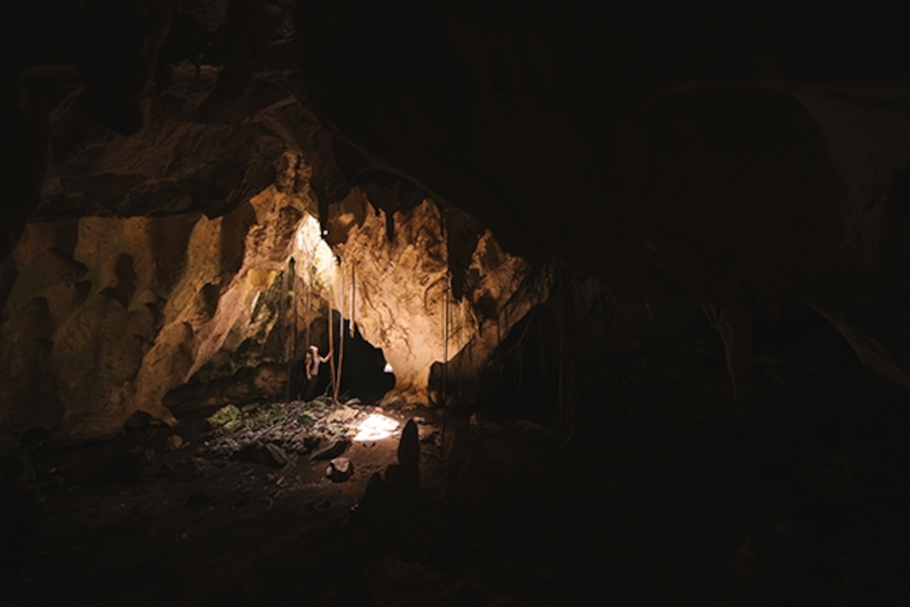 Adventure filmmaker Tahria Sheather looks up into a porthole in the cave complex deep on Long Island, Bahamas; Photograph by Max Lowe