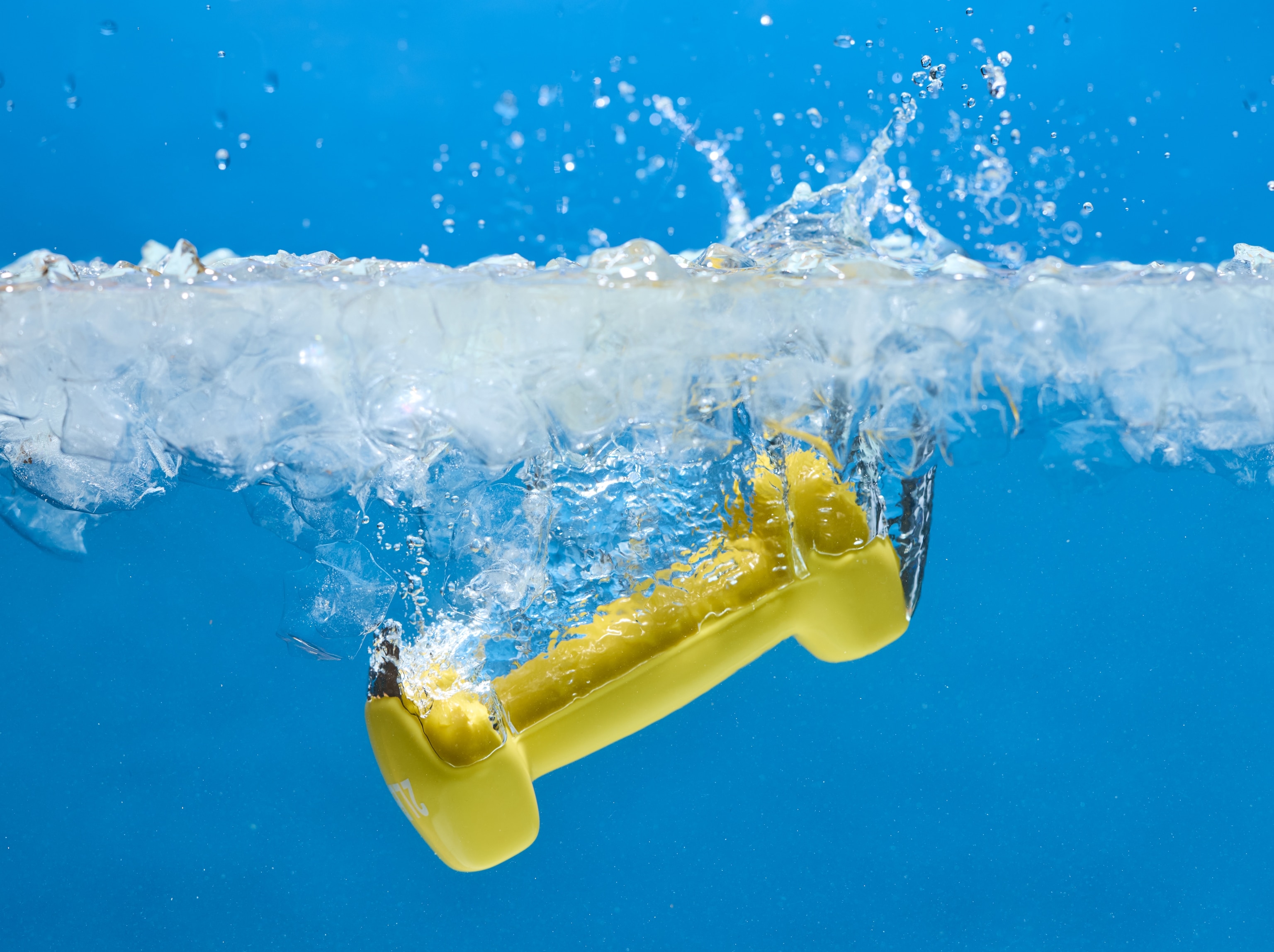 A yellow dumbbell falls into ice water.